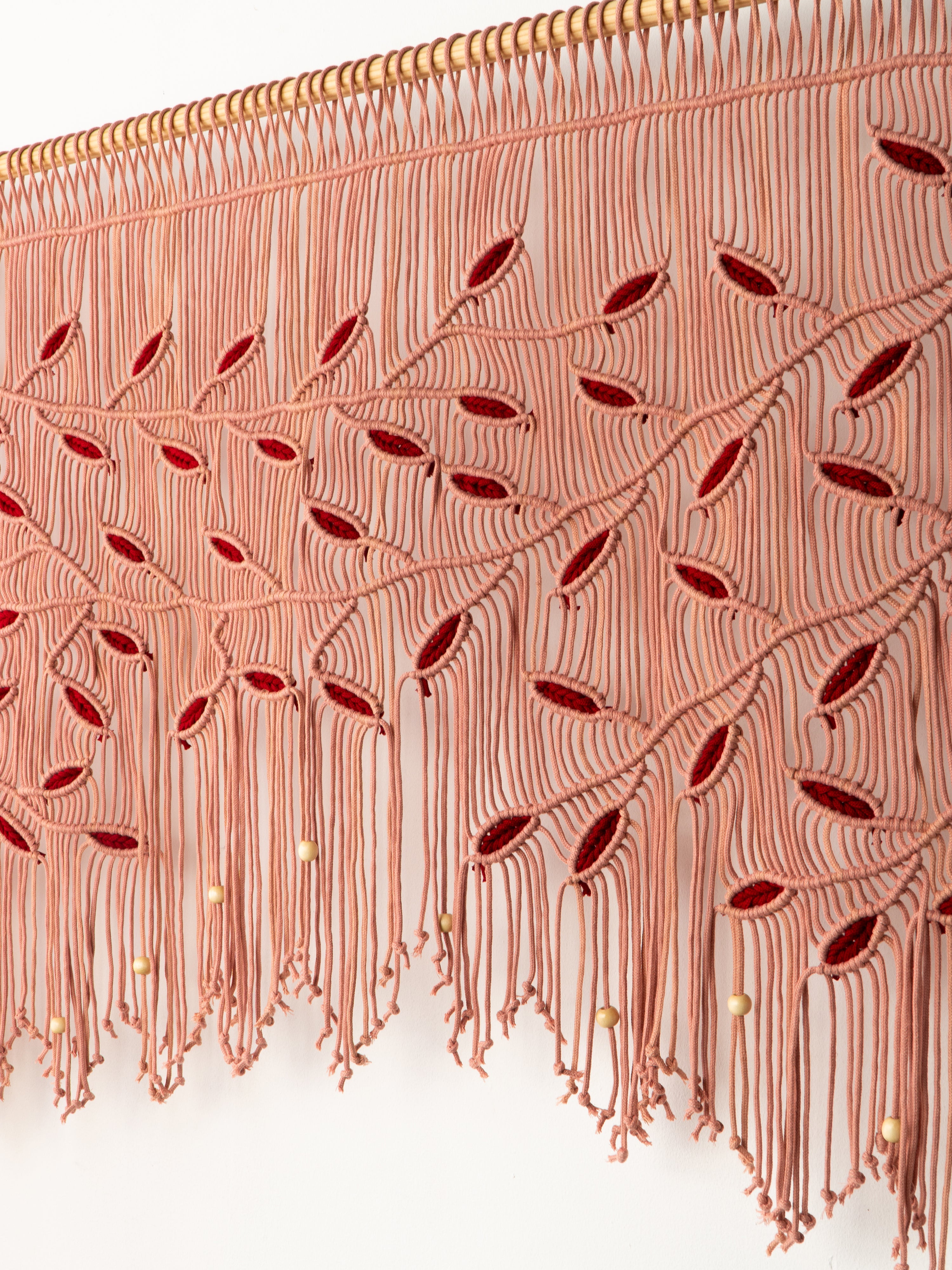 Close-up of a decorative fabric with intricate patterns and red accents on a white background