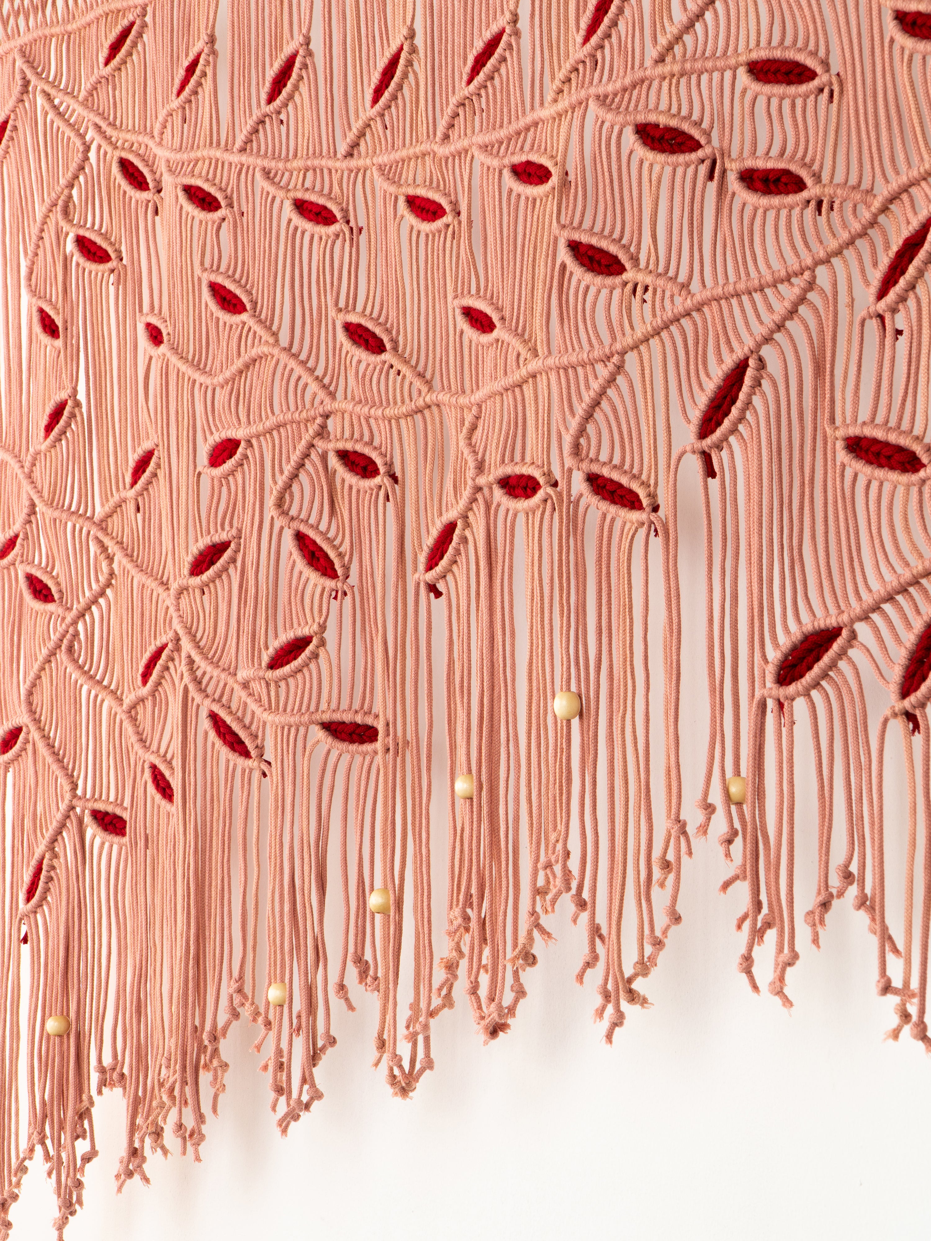 Close-up of a textured fabric with red and gold patterns on a white background