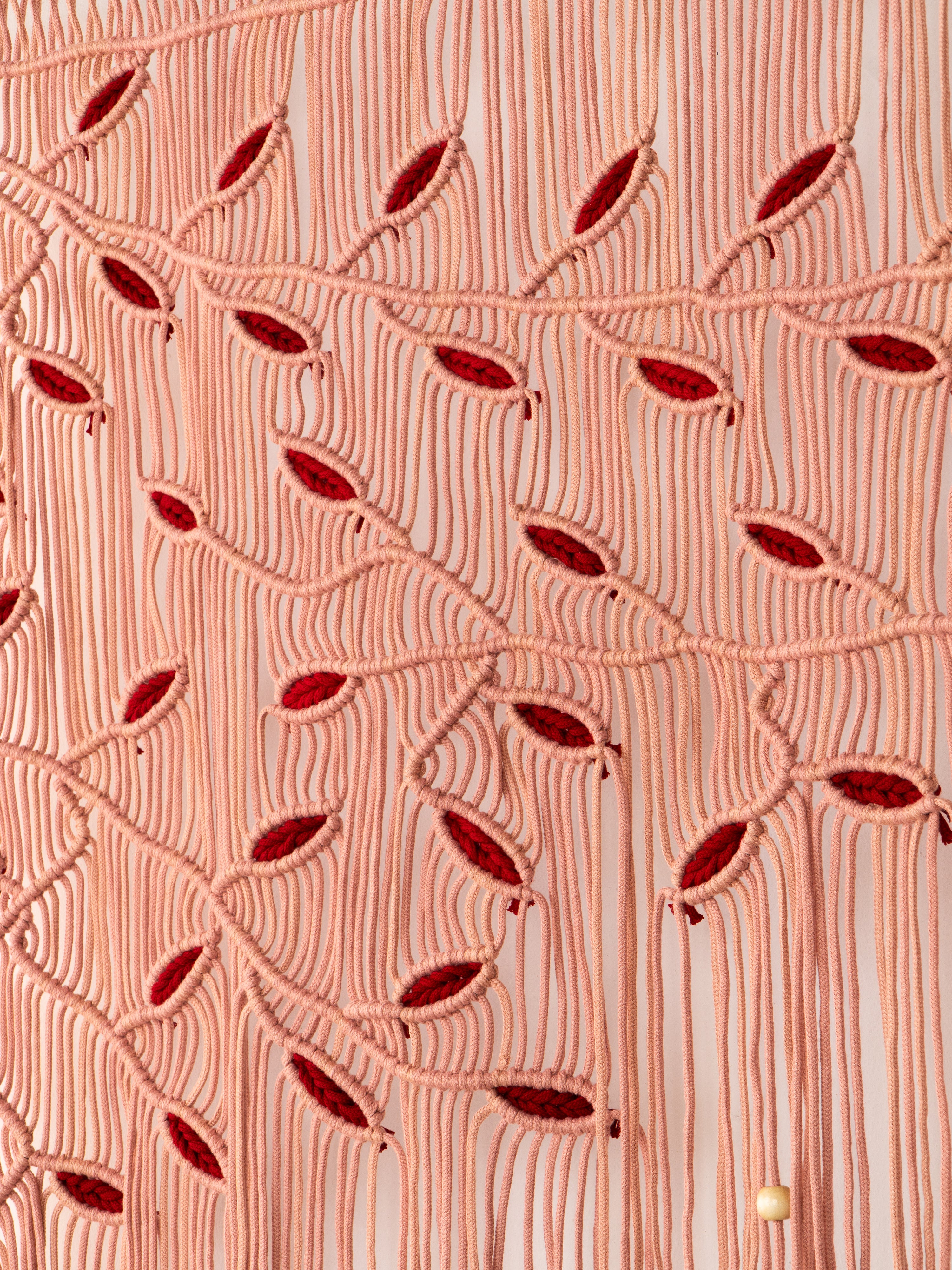 Close-up of a textured fabric with red leaf patterns on a pink background