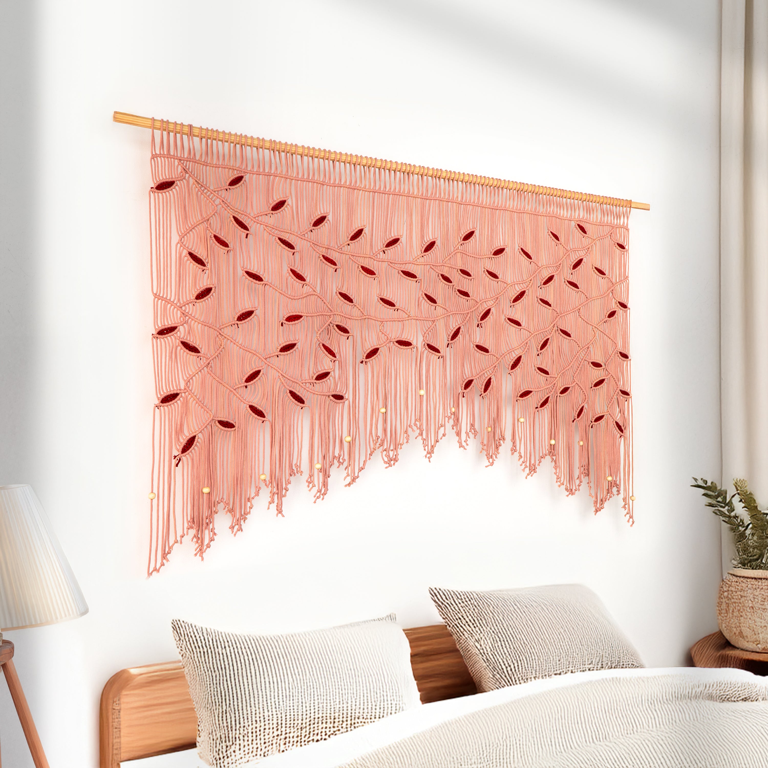 Decorative pink macrame wall hanging above a bed with white bedding and pillows.
