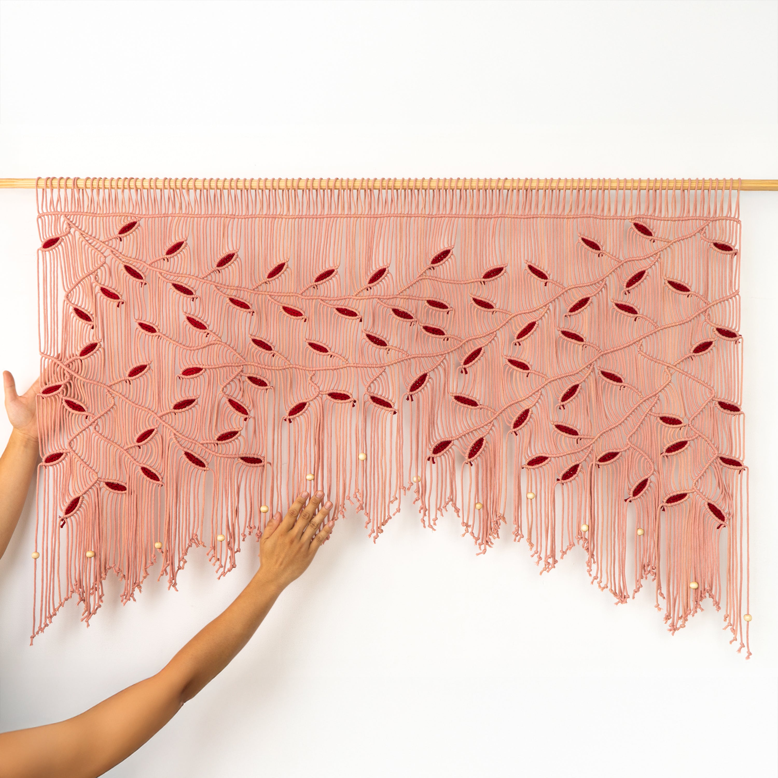 Handmade pink string art with red beads on a white background