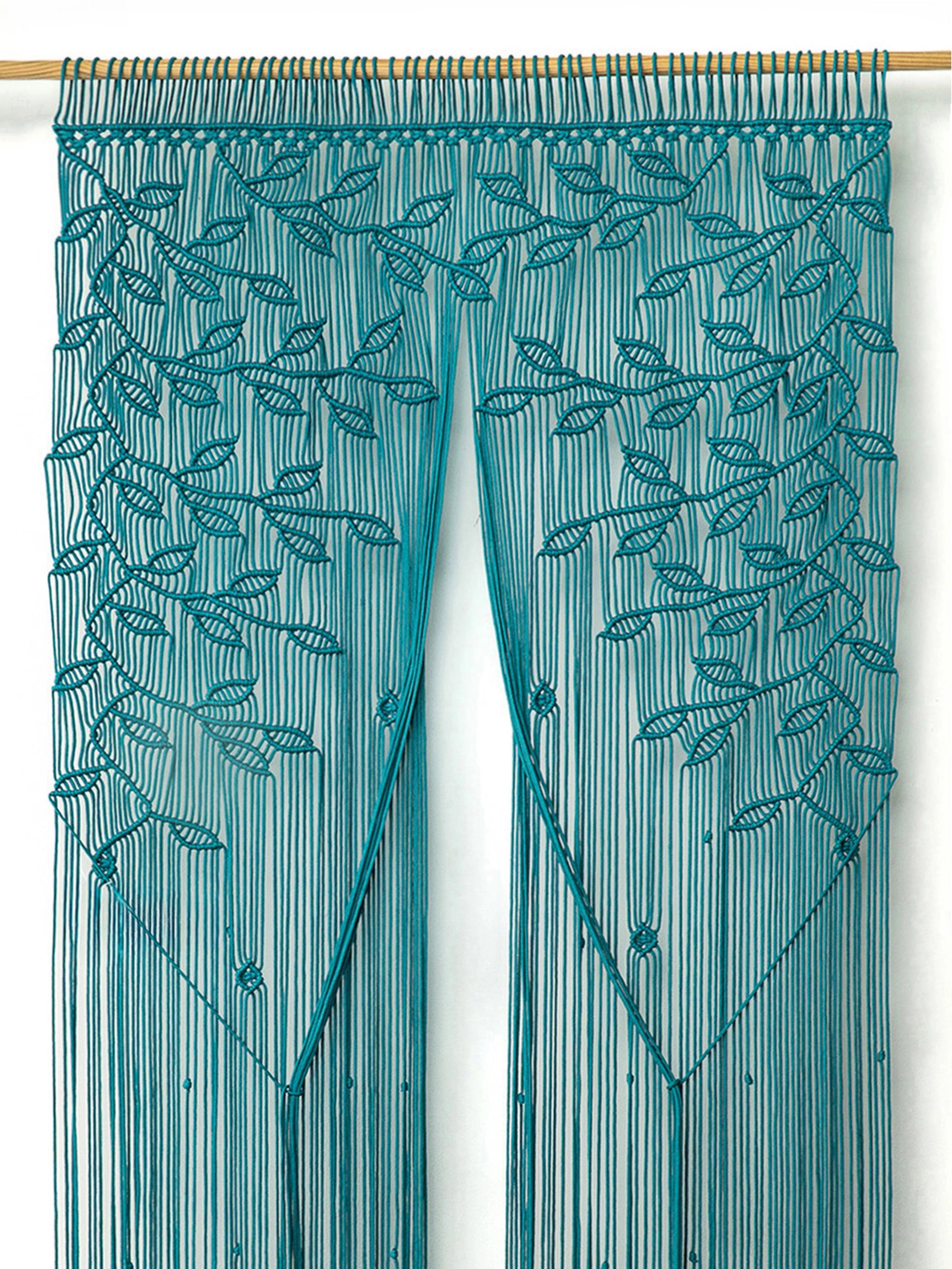 Coastal bohemian interior decor showcasing a large vibrant aqua macrame tapestry hung across a doorway arch.