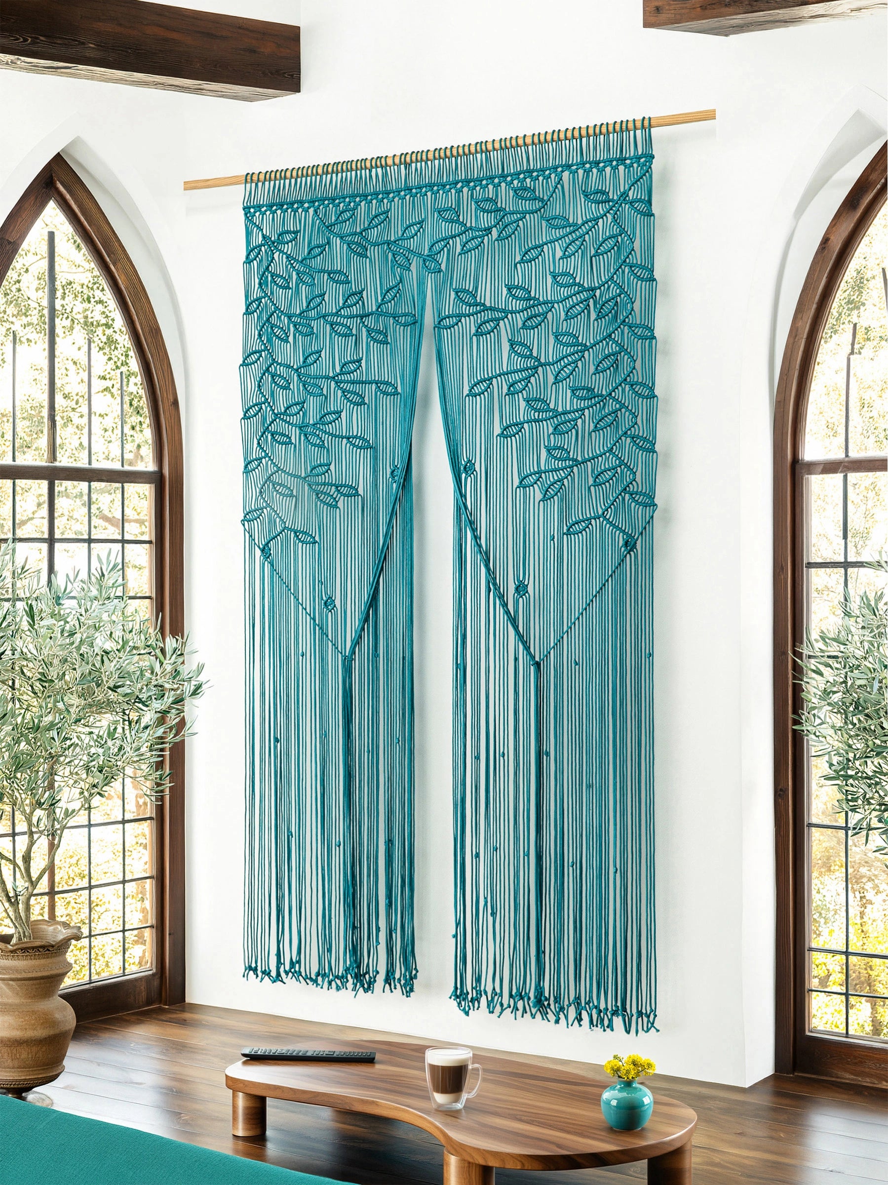 Large deep aqua macrame doorway curtain with weeping botanical leaf knotting tied back in a modern home entryway.