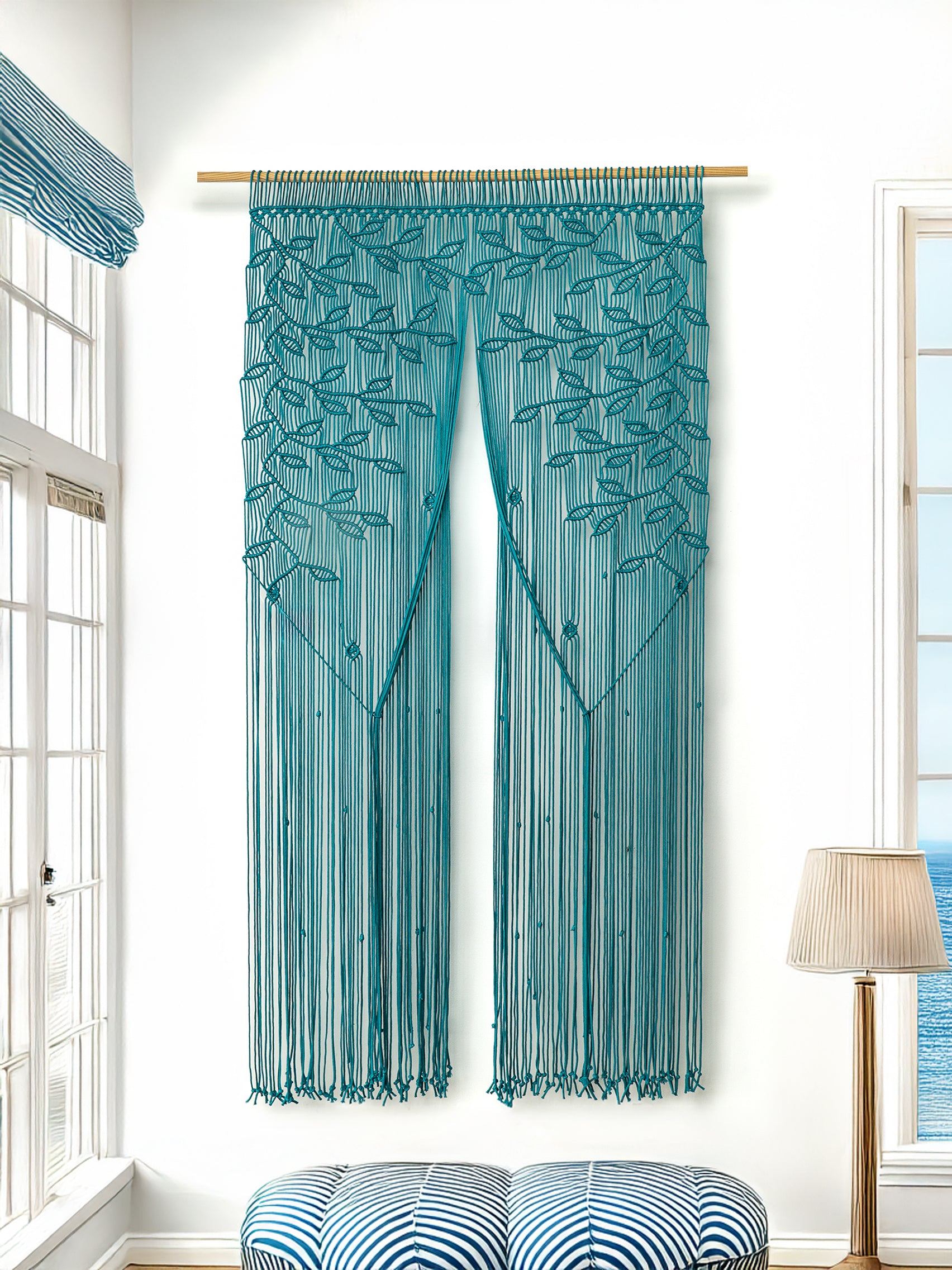 Teal string curtain with leaf pattern in a room with windows and a lamp.