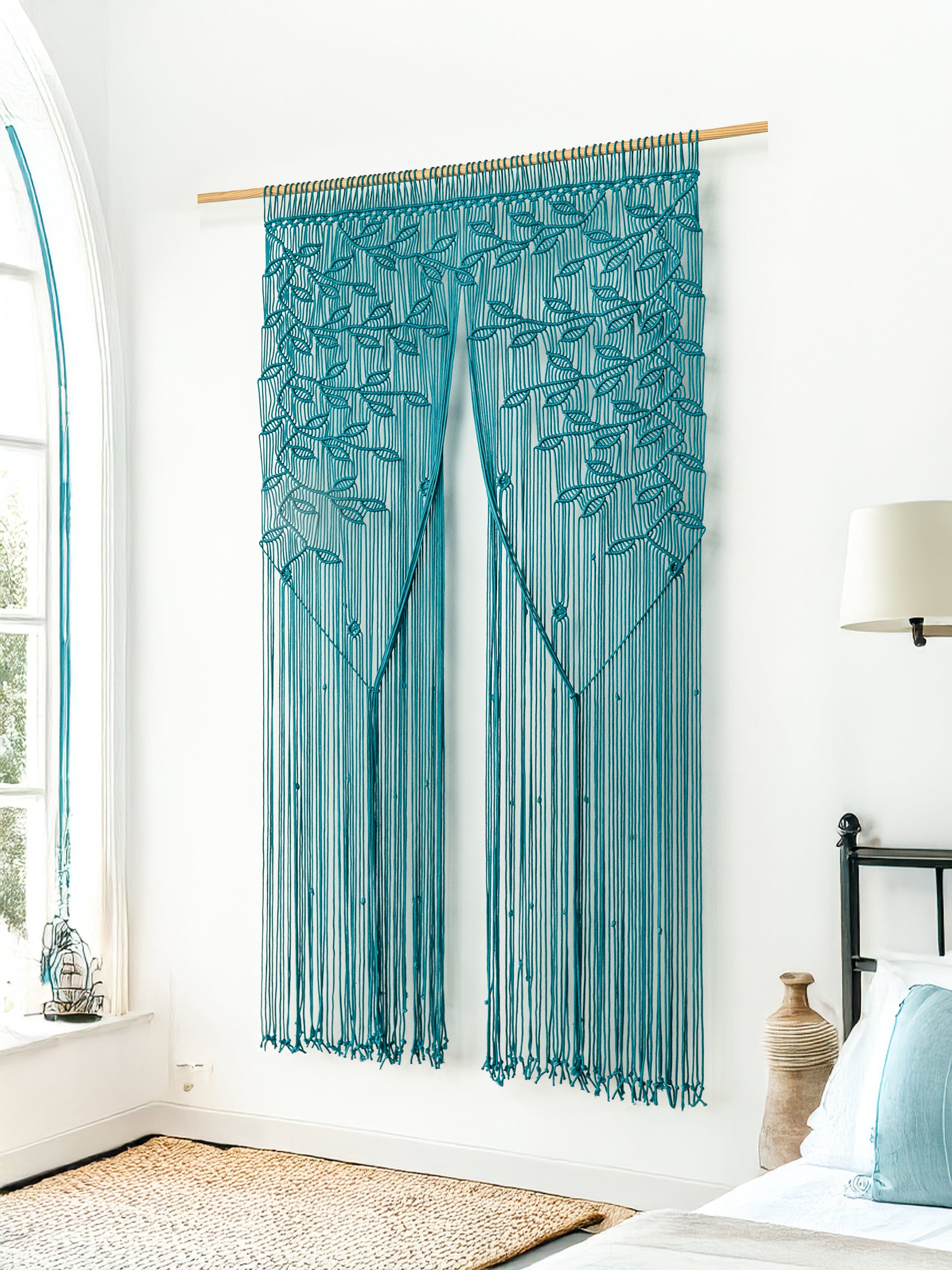 Teal string curtain hanging in a room with a bed and lamp.