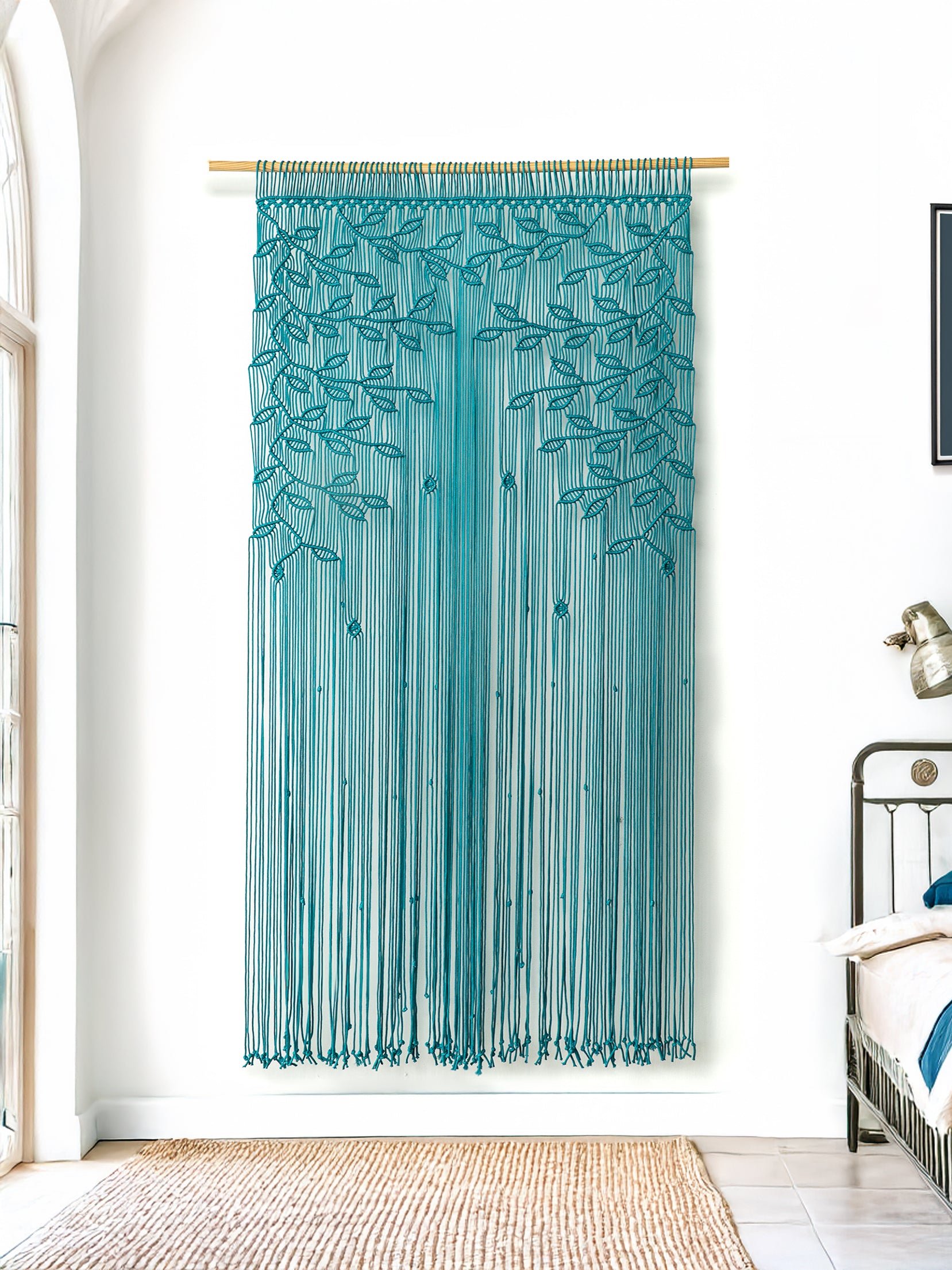 Teal string curtain hanging in a room with a bed and lamp.