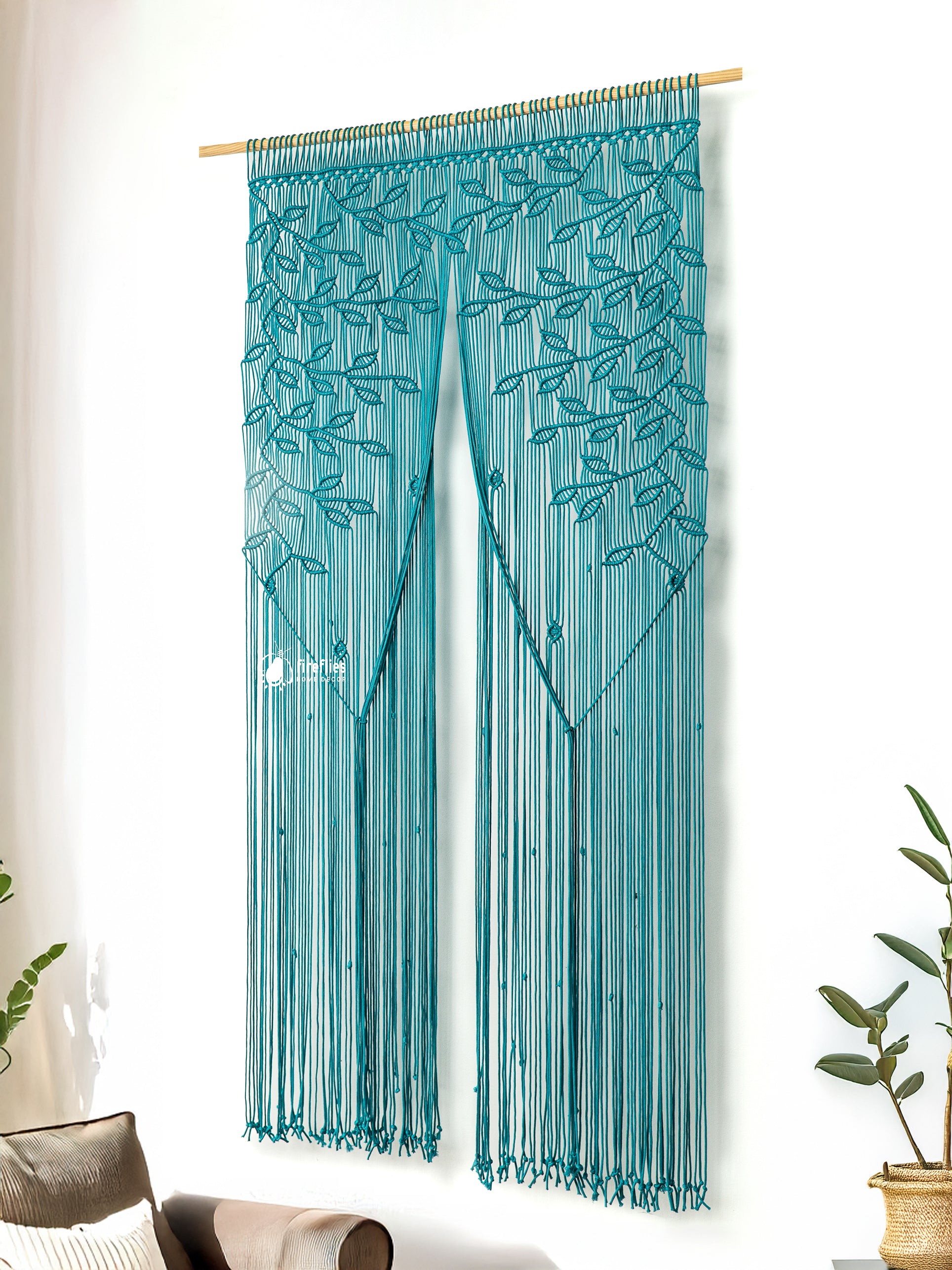 Teal string curtain with leaf pattern hanging in a room with plants.