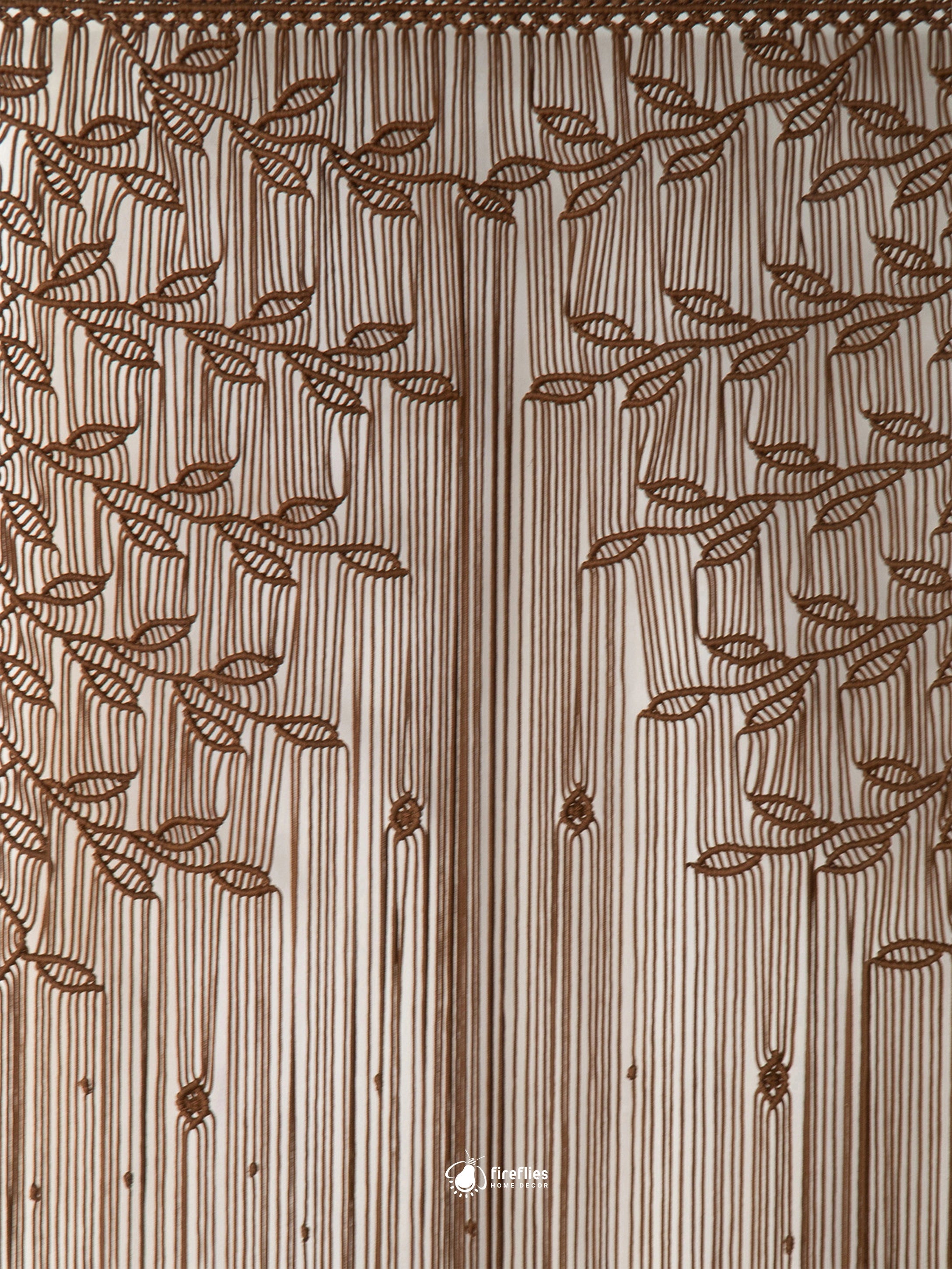 A close-up of a curtain panel featuring a brown embroidered leaf and vine pattern over a beige and white striped fabric background.