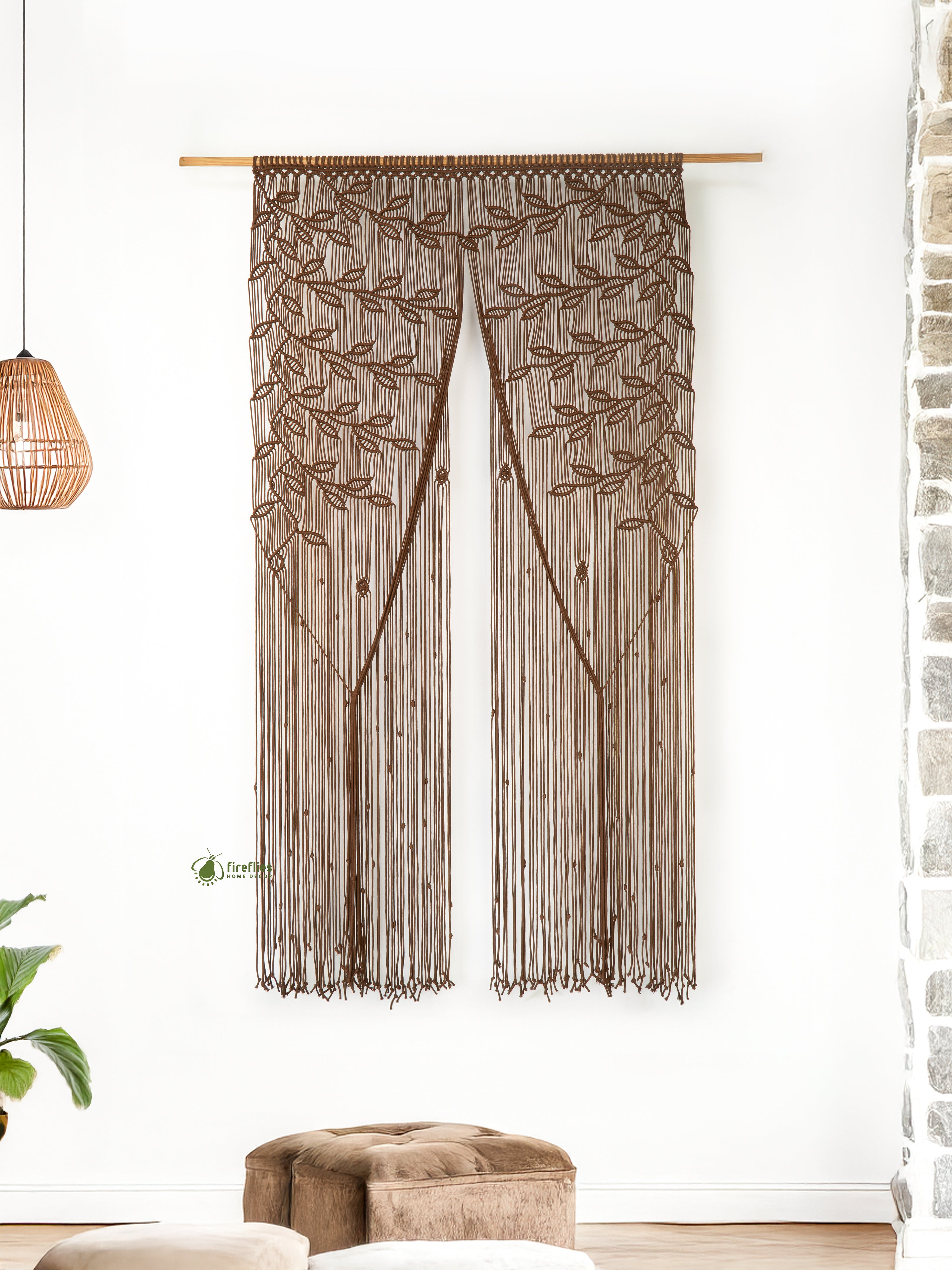Decorative curtain with leaf pattern hanging in a room with a plant and sofa.