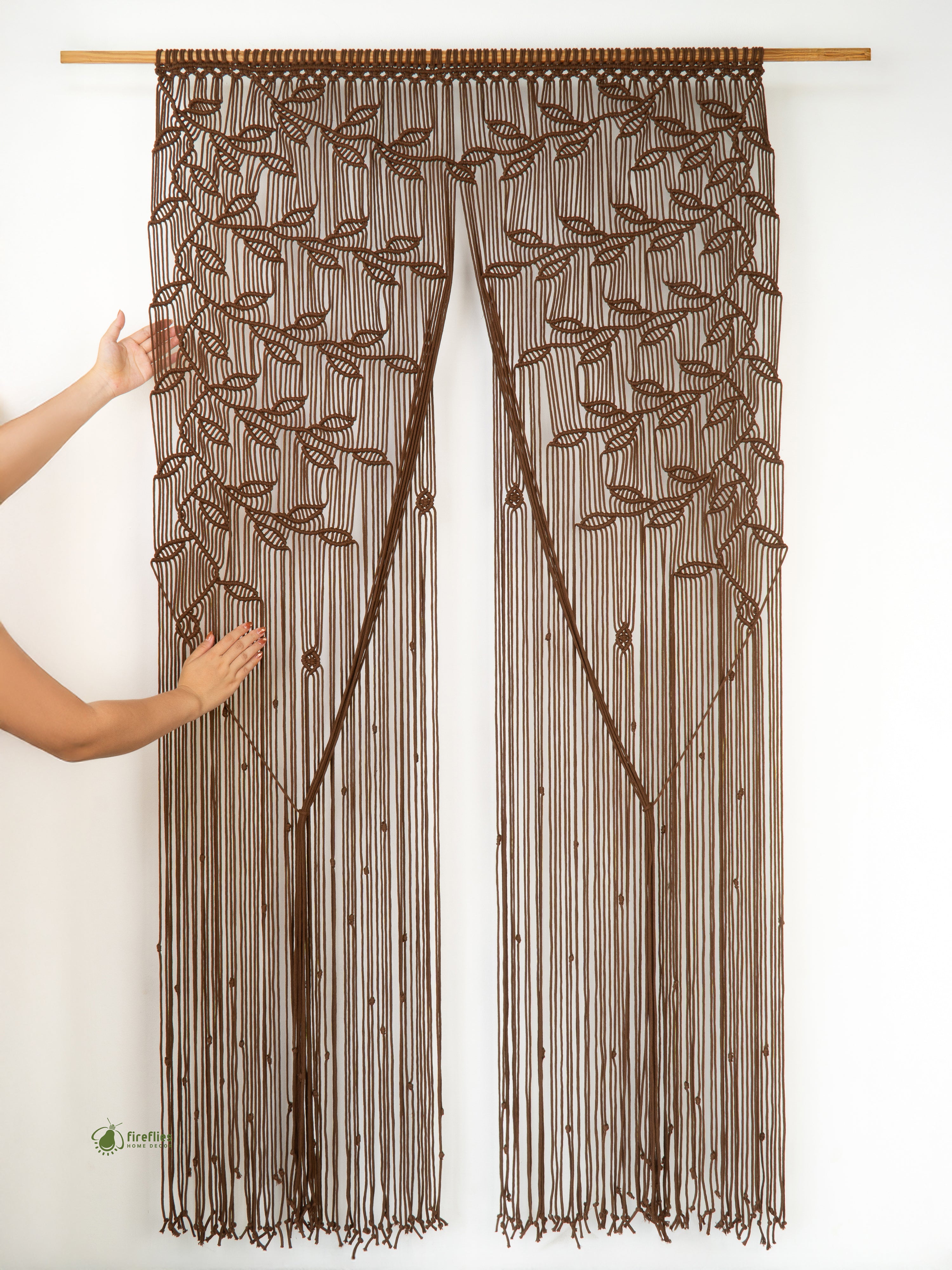 Brown beaded curtain with leaf pattern held up against a white background