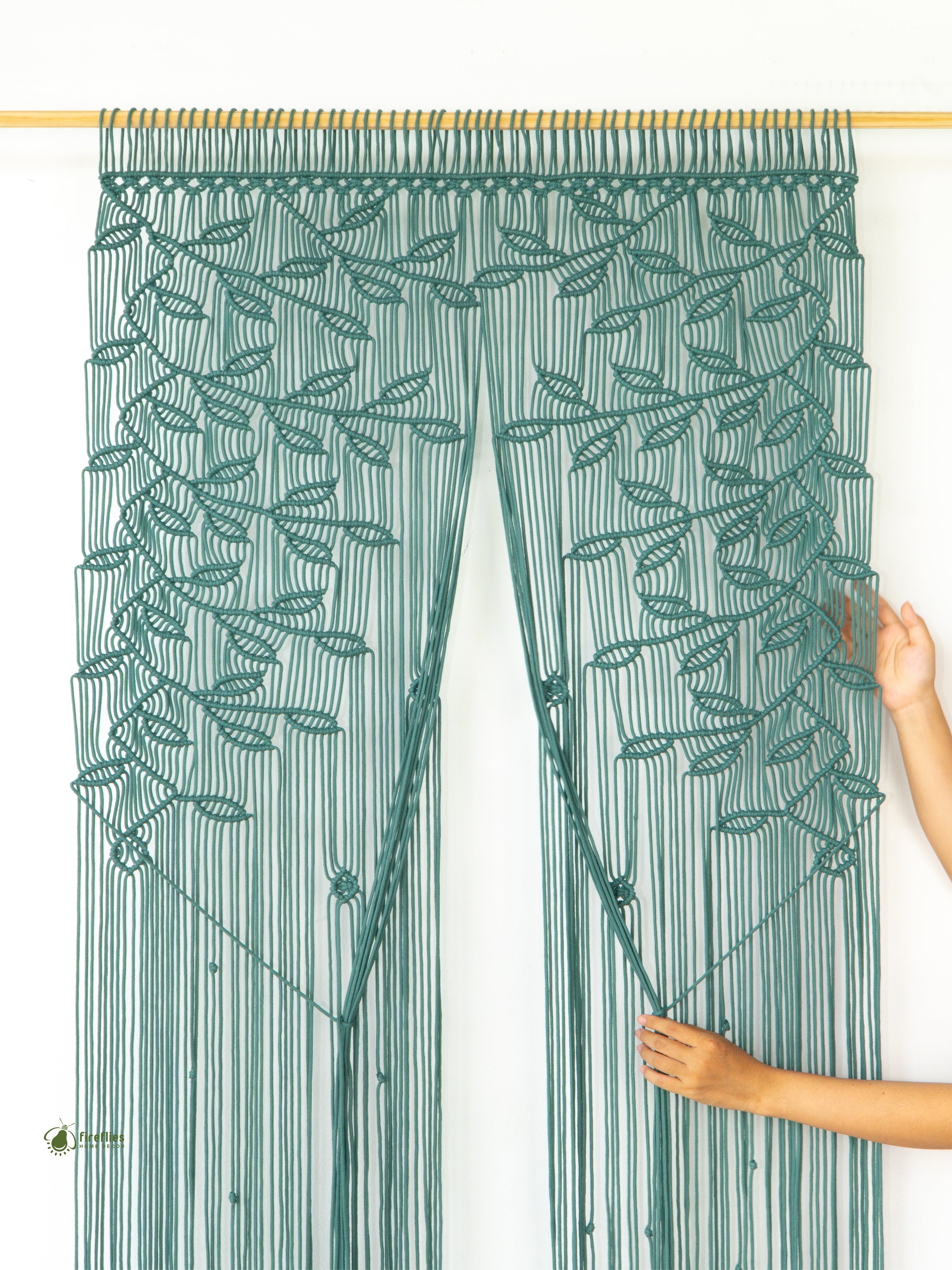 Green string curtain with leaf pattern held by a person against a white background