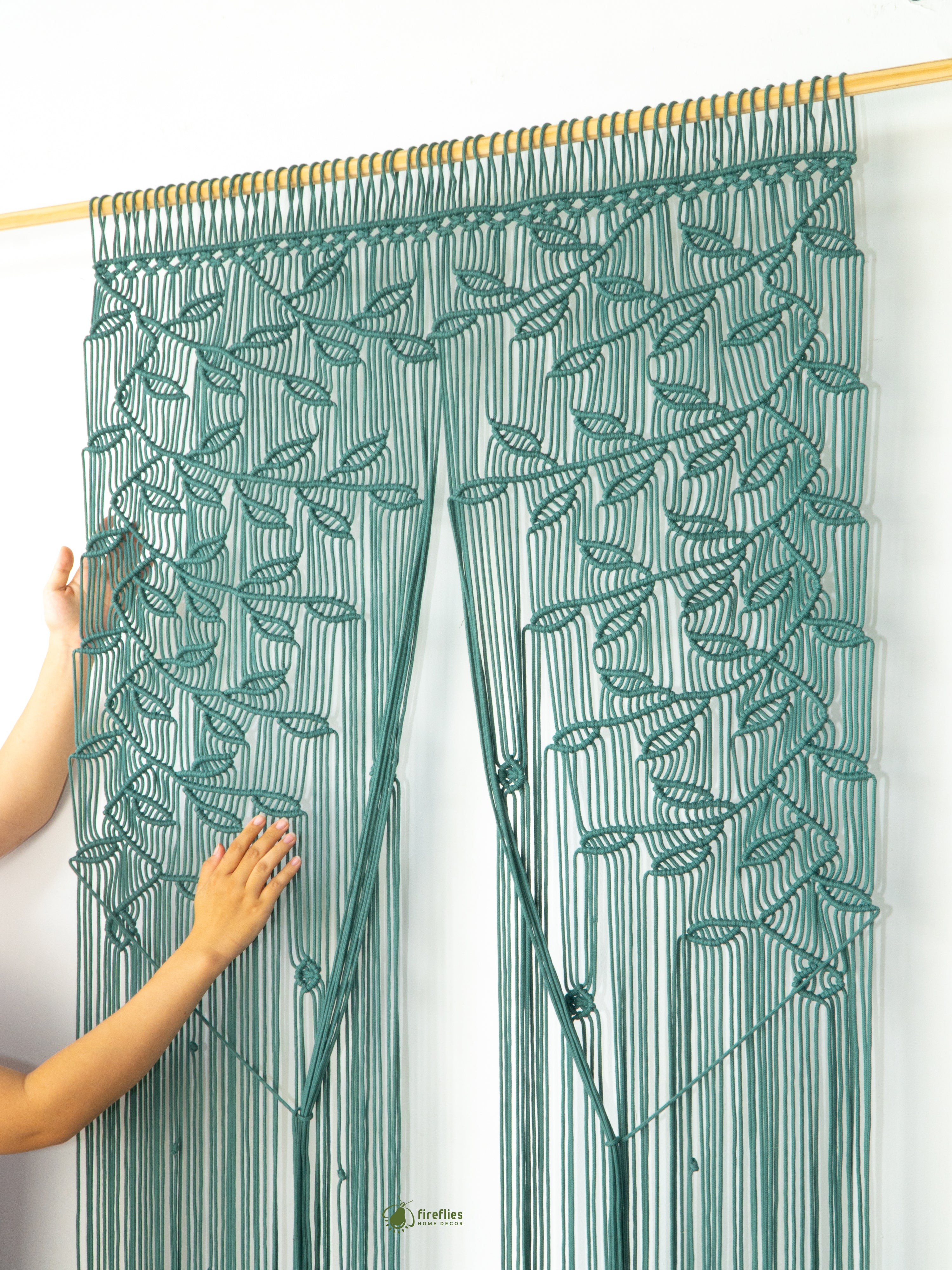 Green leaf-patterned string curtain held by a person against a white background