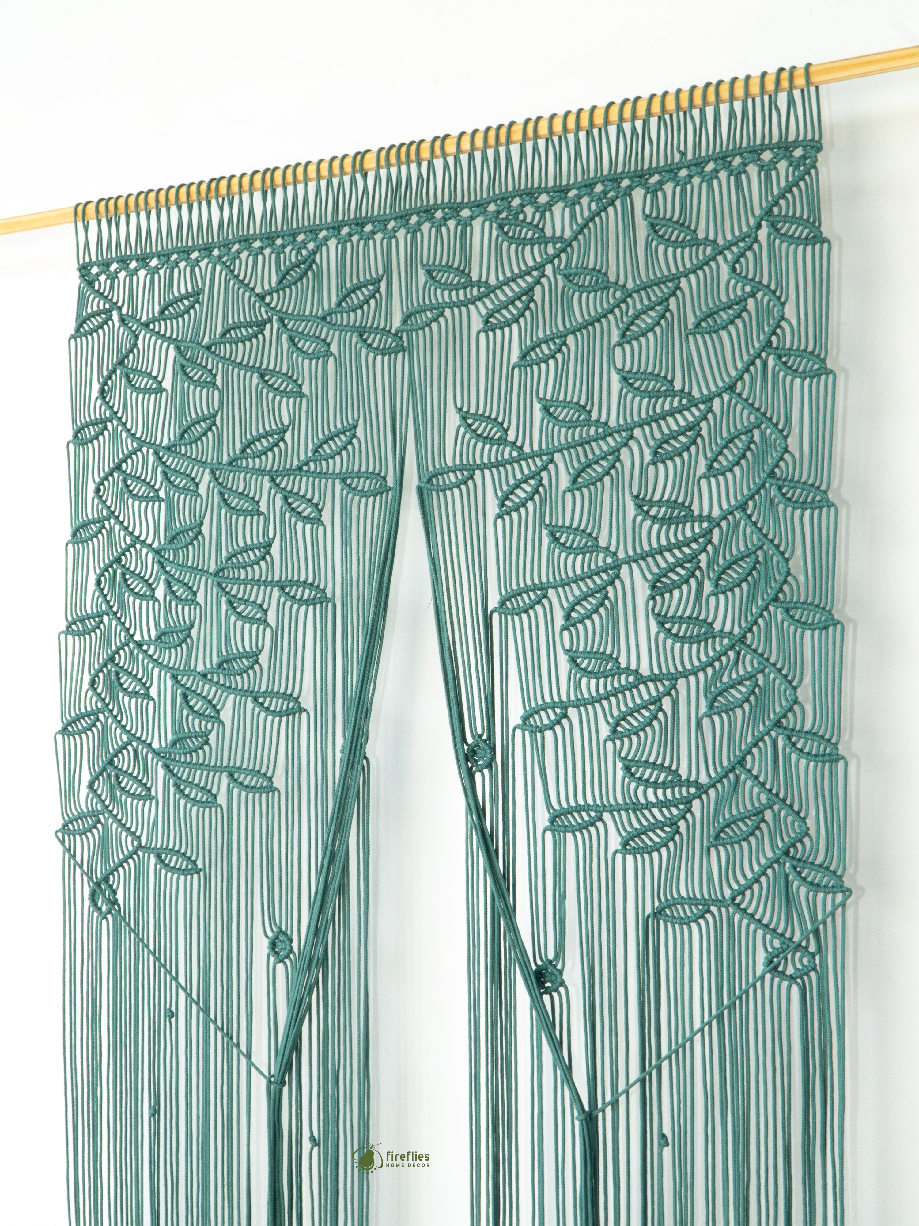 Green leaf-patterned curtain on a wooden rod against a white background