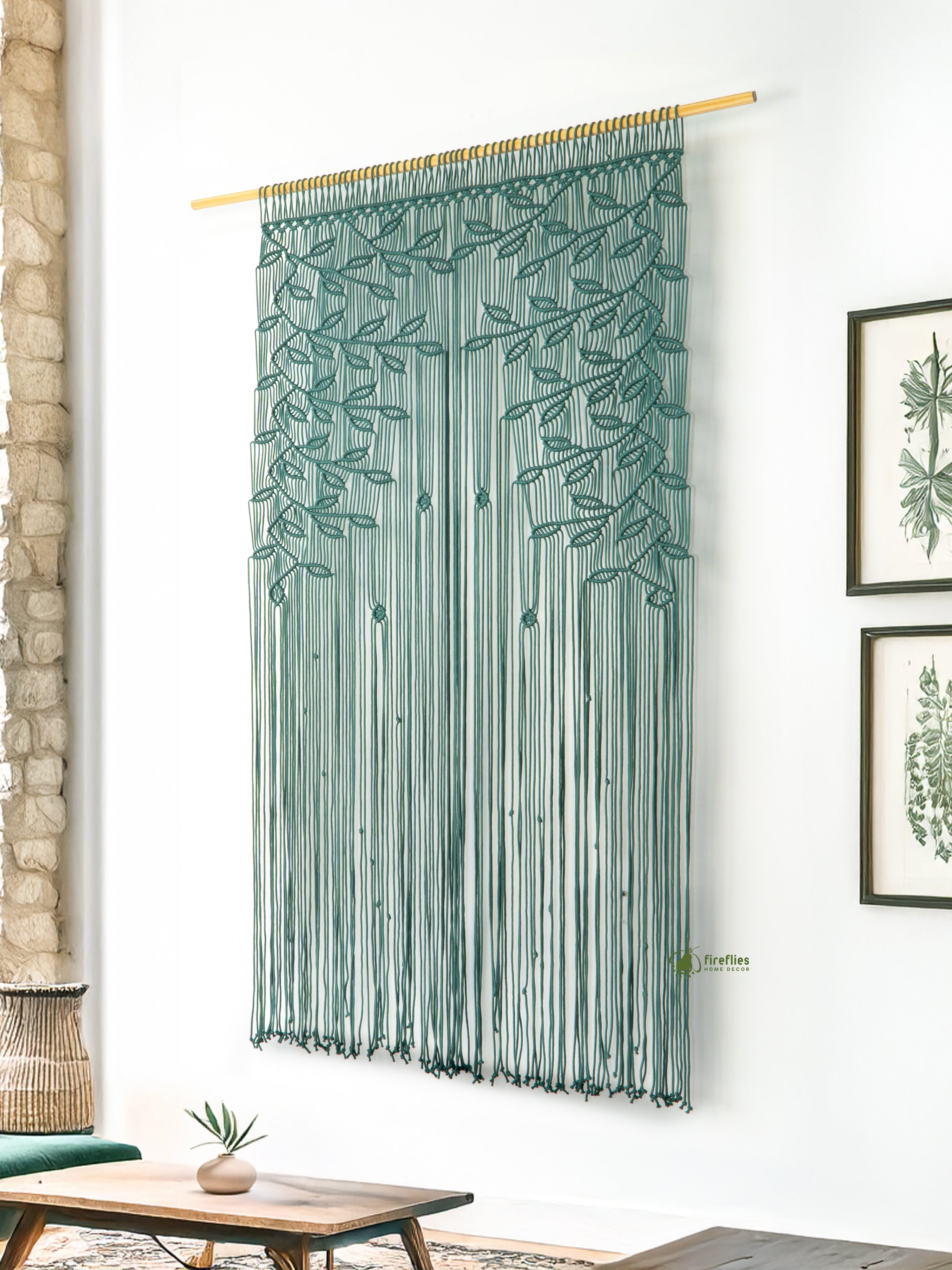 Decorative string curtain with leaf pattern hanging in a room with a stone wall and wooden coffee table.