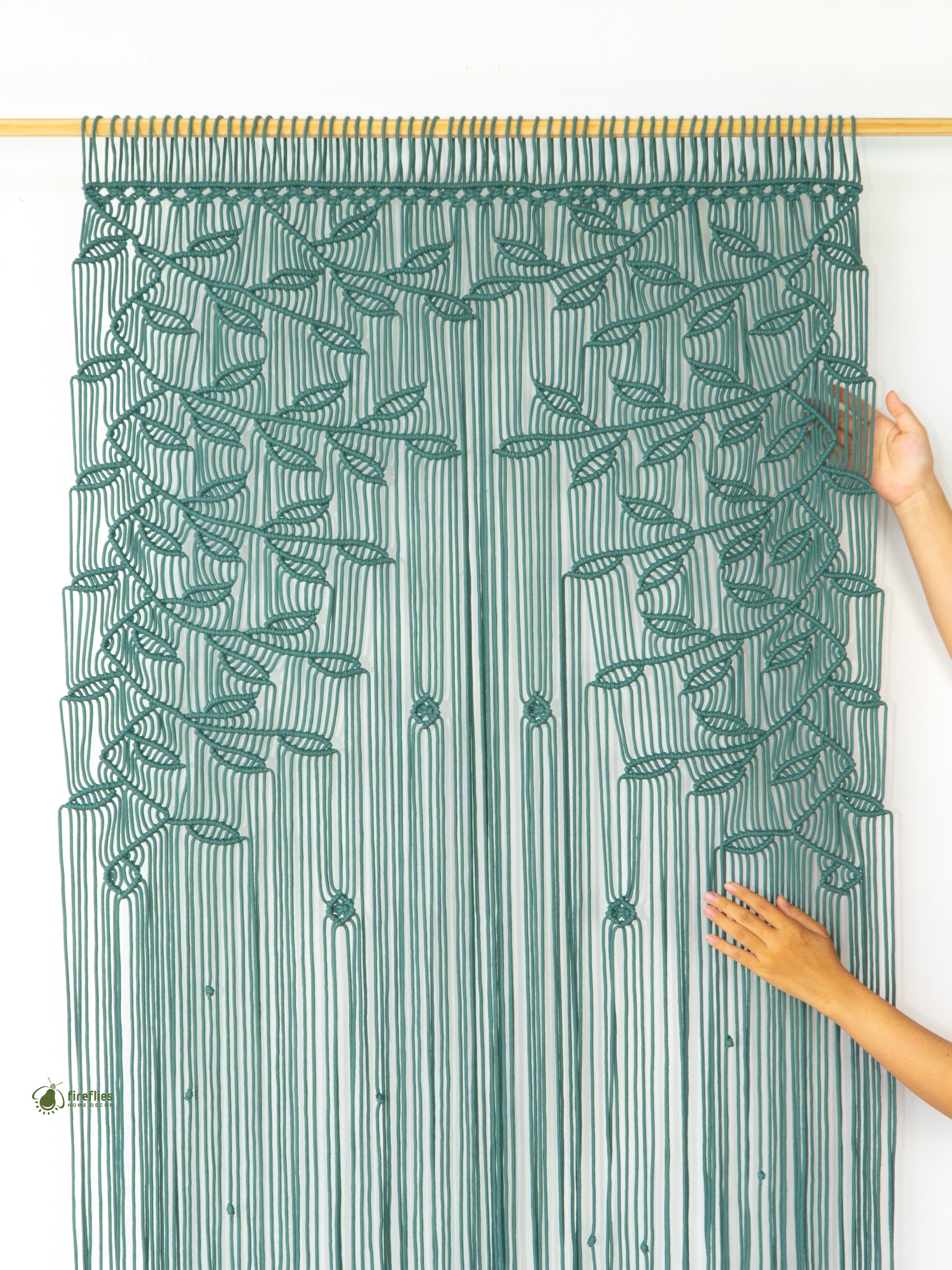 Textured green curtain with leaf pattern being held by a person against a white background