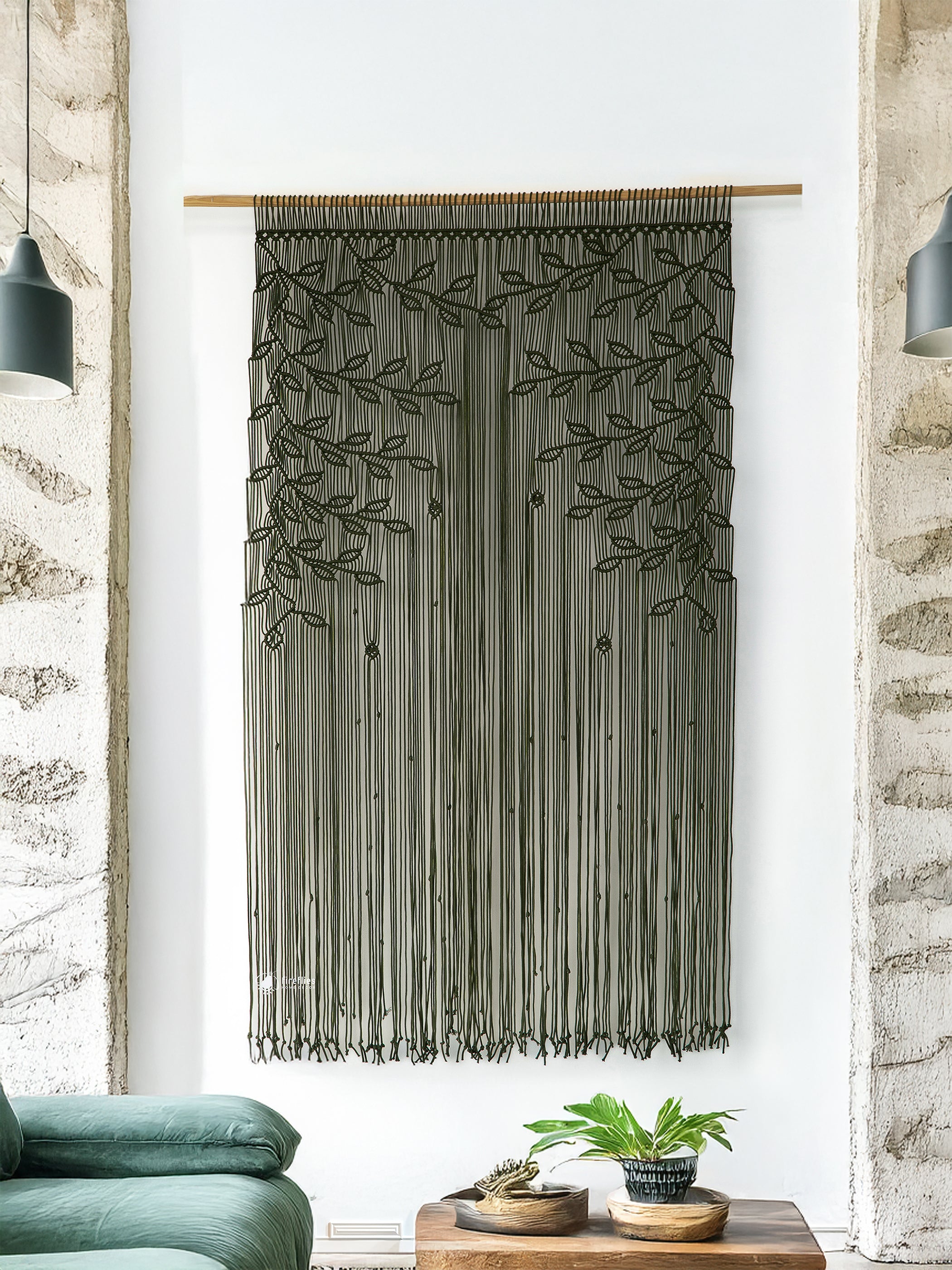 Textile wall hanging with leaf patterns in a room with a couch and plants.