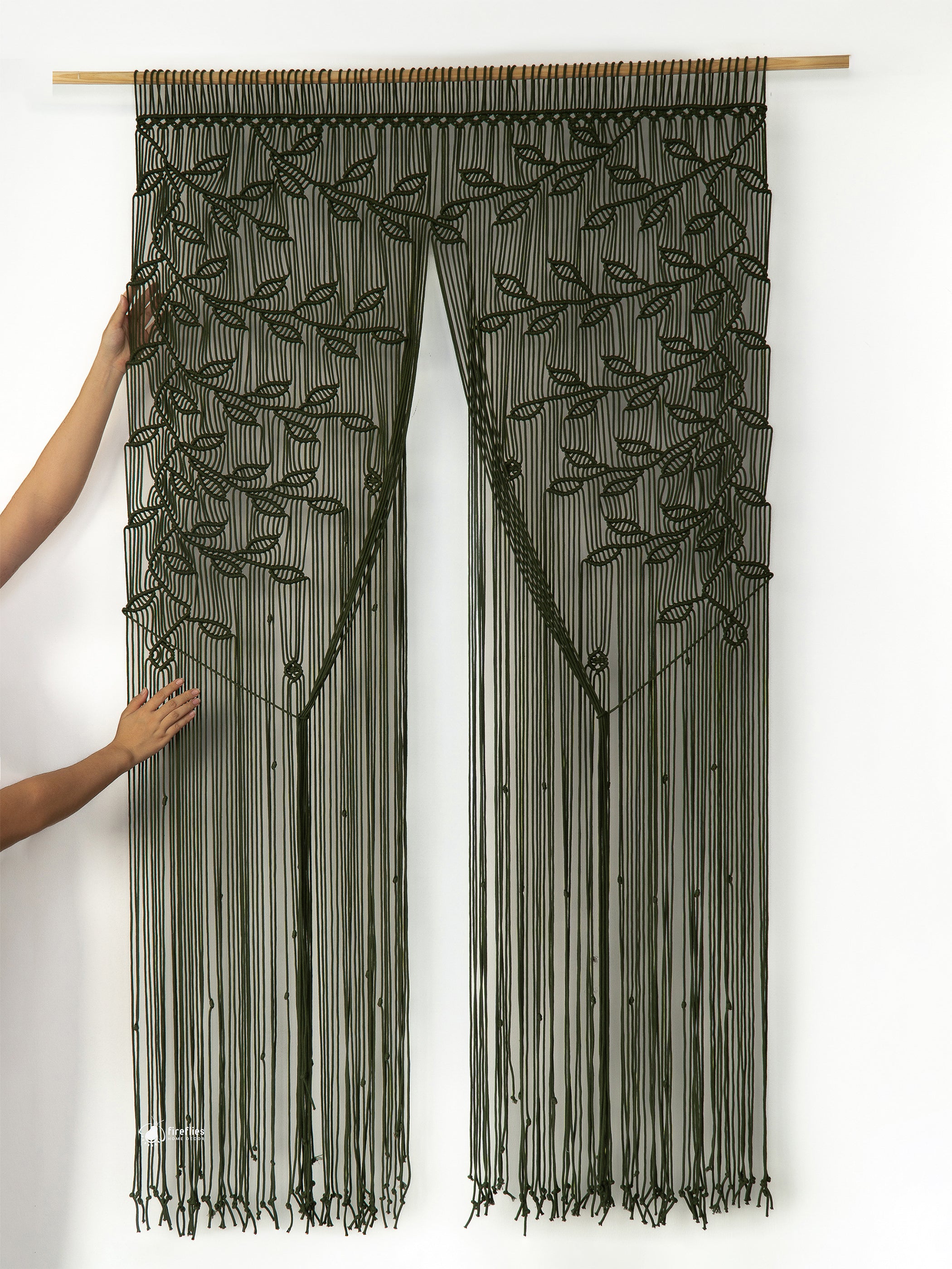 Decorative string curtain with leaf pattern held by a person against a white background