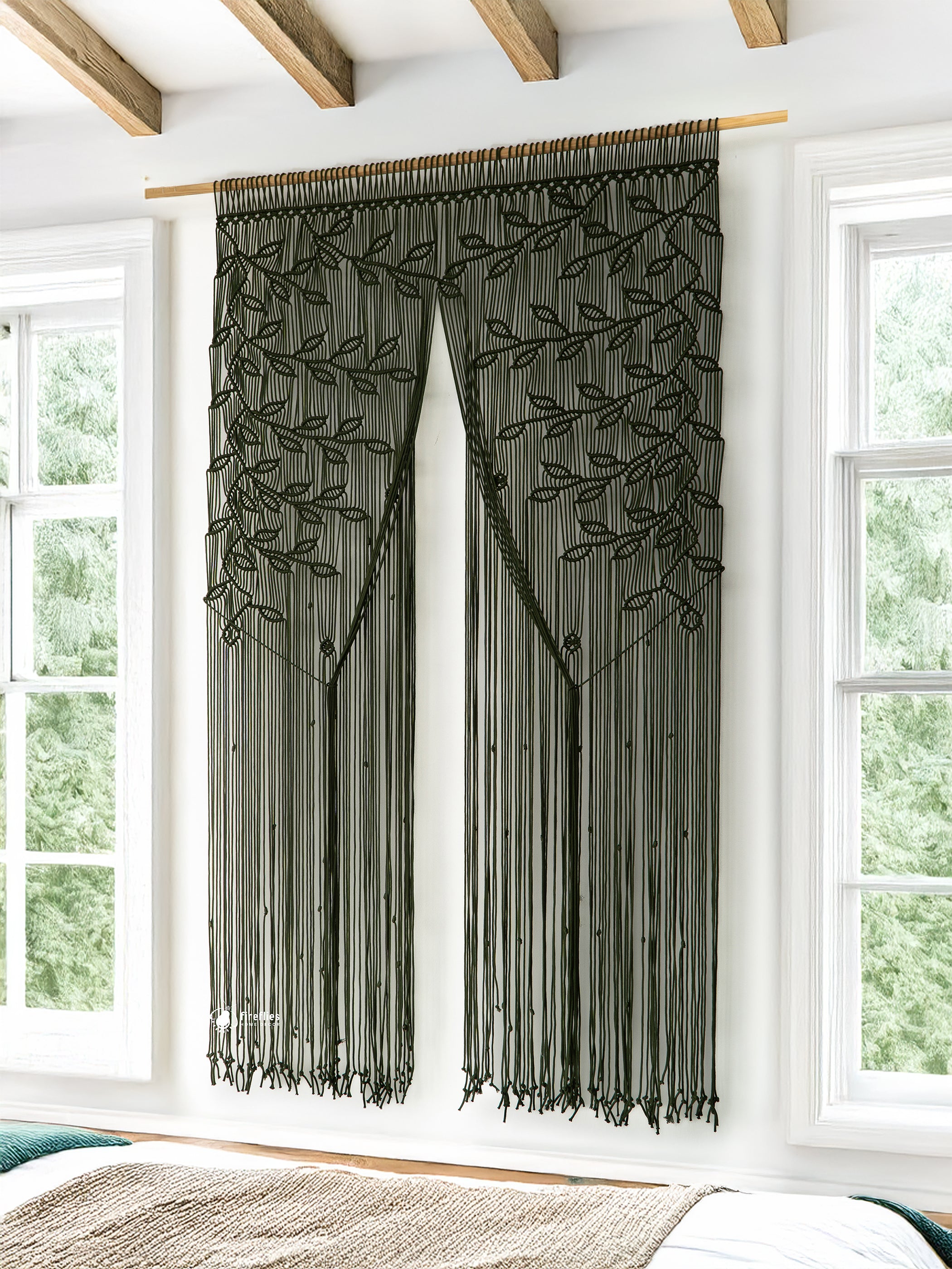 Decorative black curtain with leaf pattern hanging in a room with large windows.