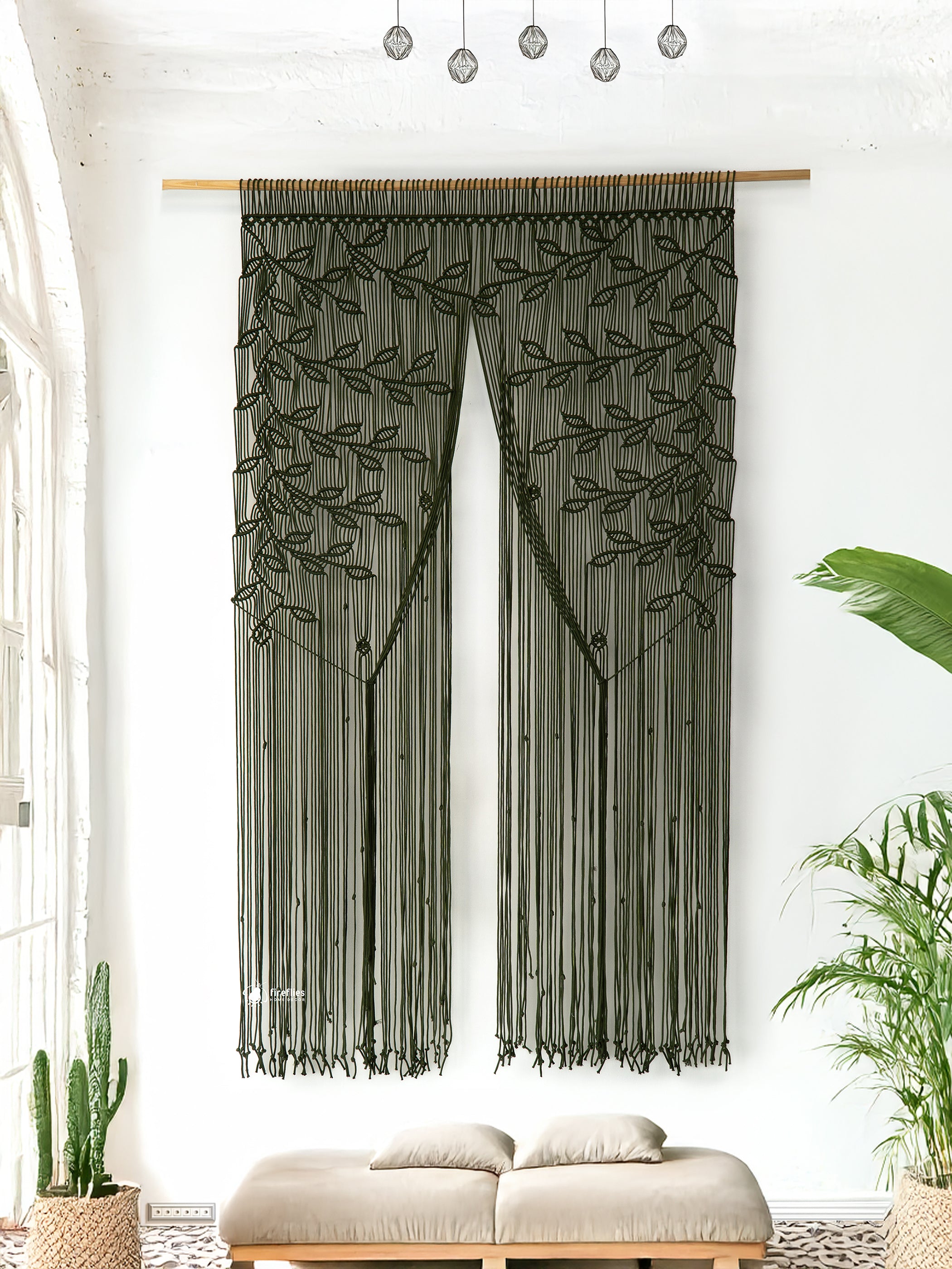 Decorative curtain with leaf pattern hanging in a room with plants and a sofa.