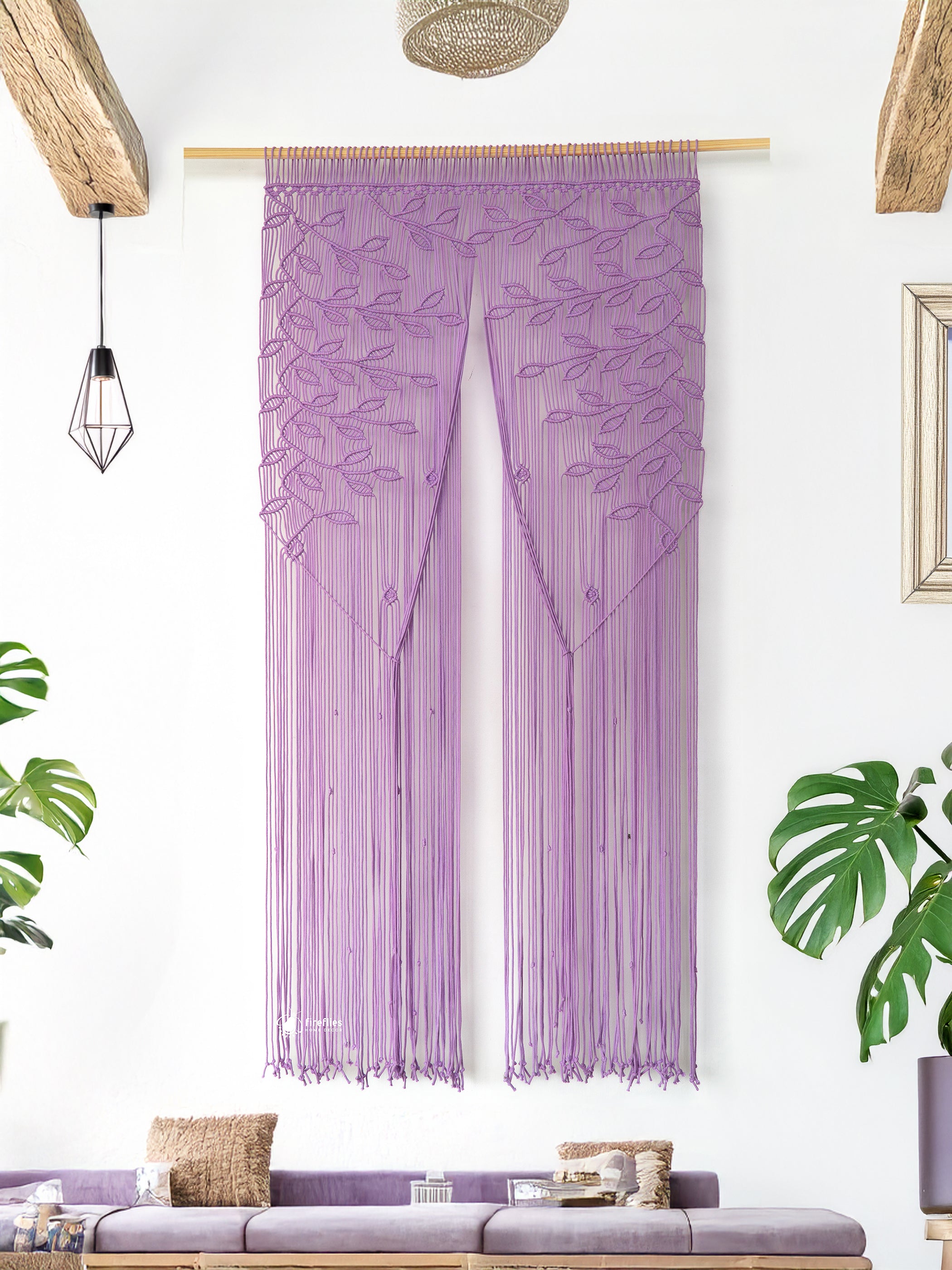 Decorative curtain with leaf pattern hanging in a room with plants and a sofa.