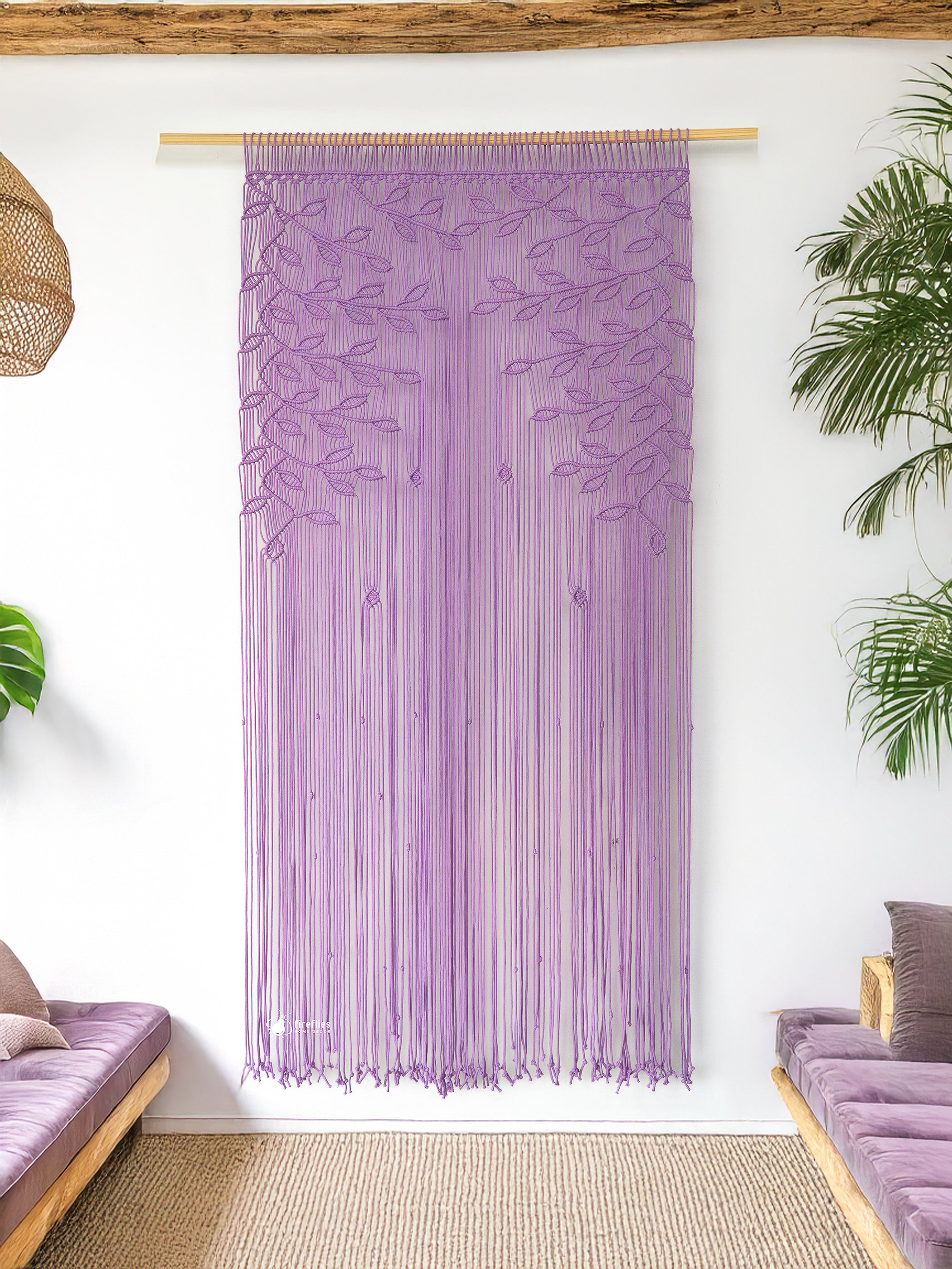 Textile wall hanging with leaf patterns in a room with a couch and plants.