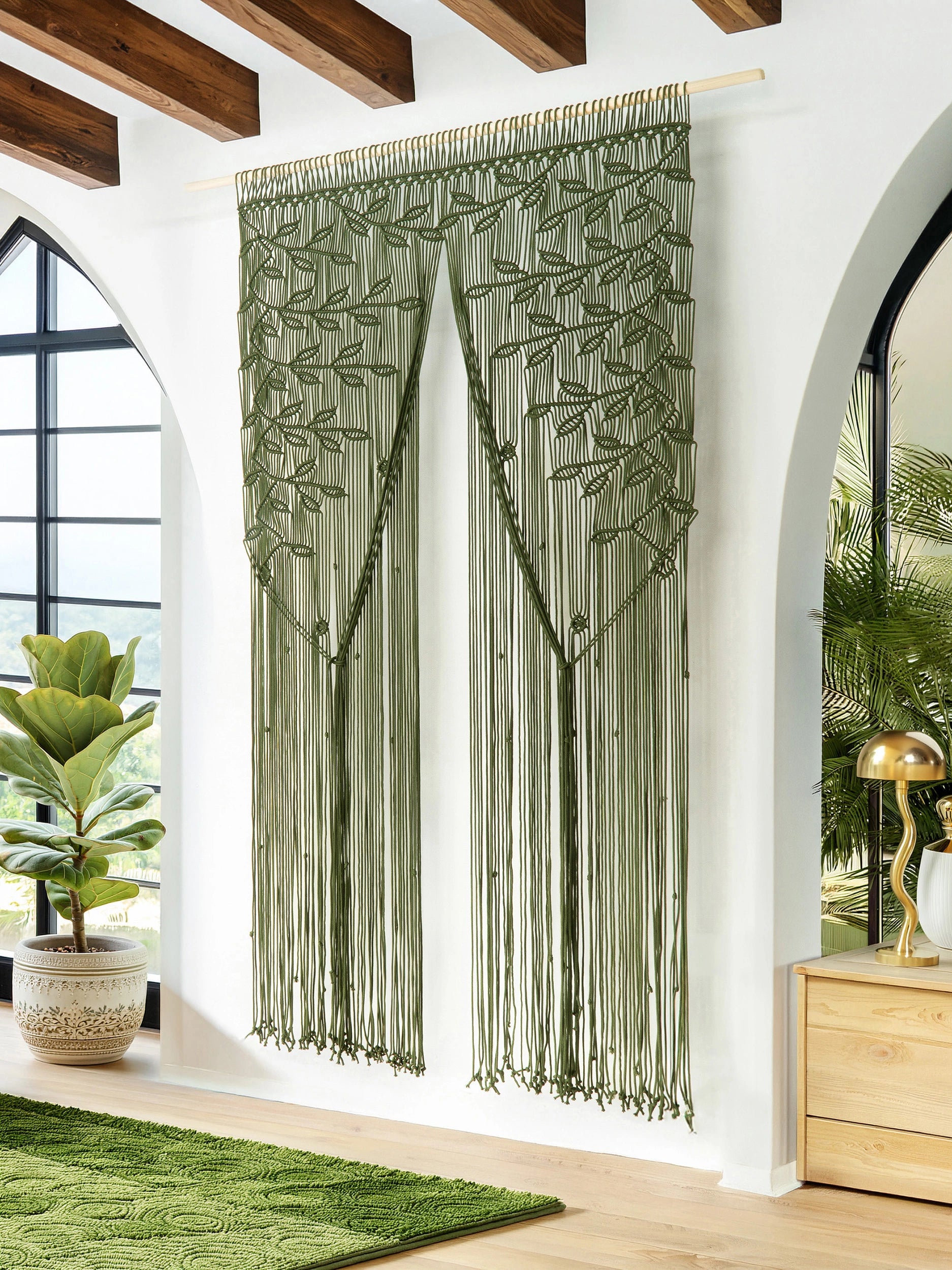 Full-length earthy olive green macrame curtain hanging between two arched windows in a bright bohemian living room.