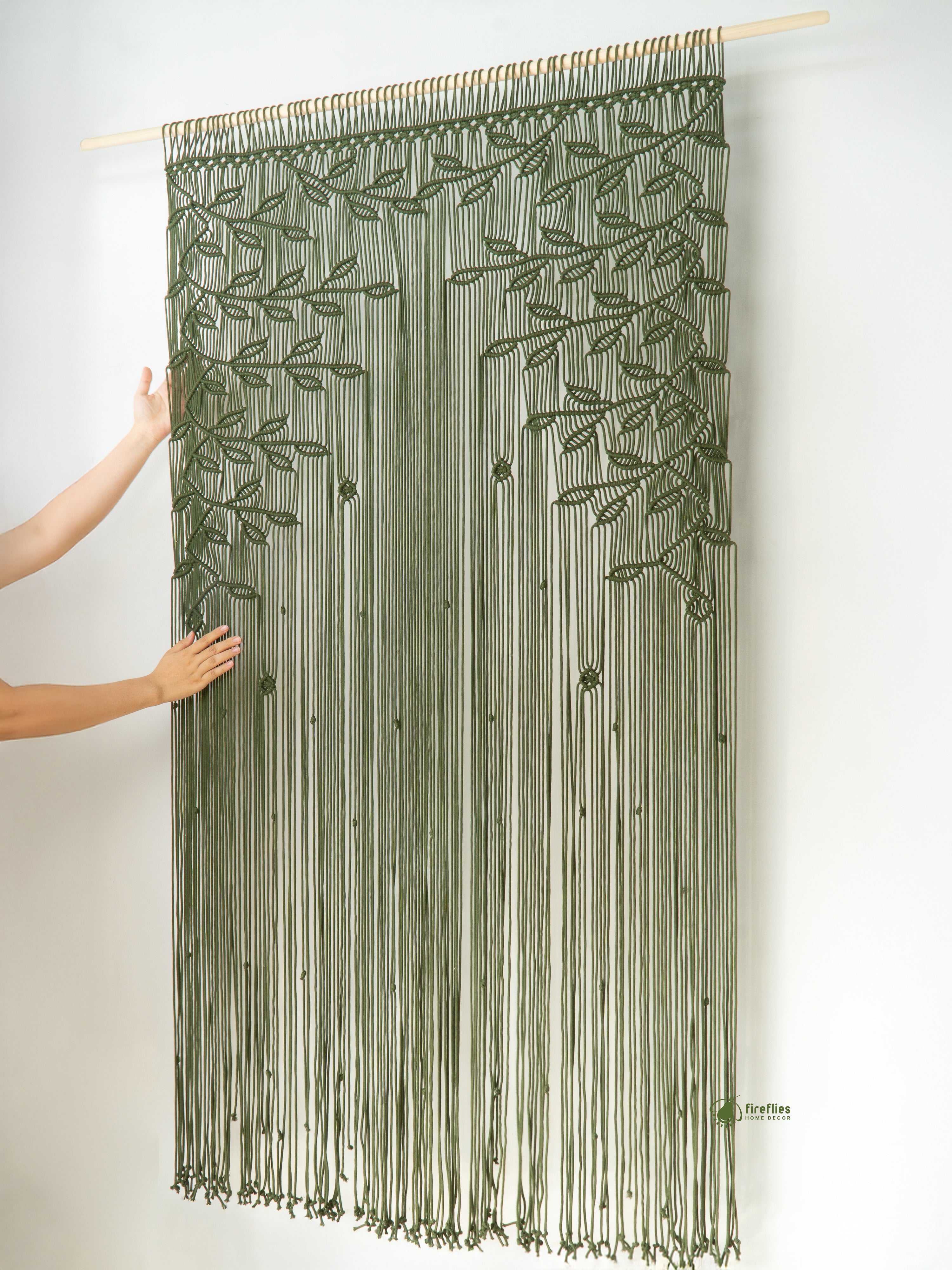 Green string curtain with leaf pattern held up against a white wall