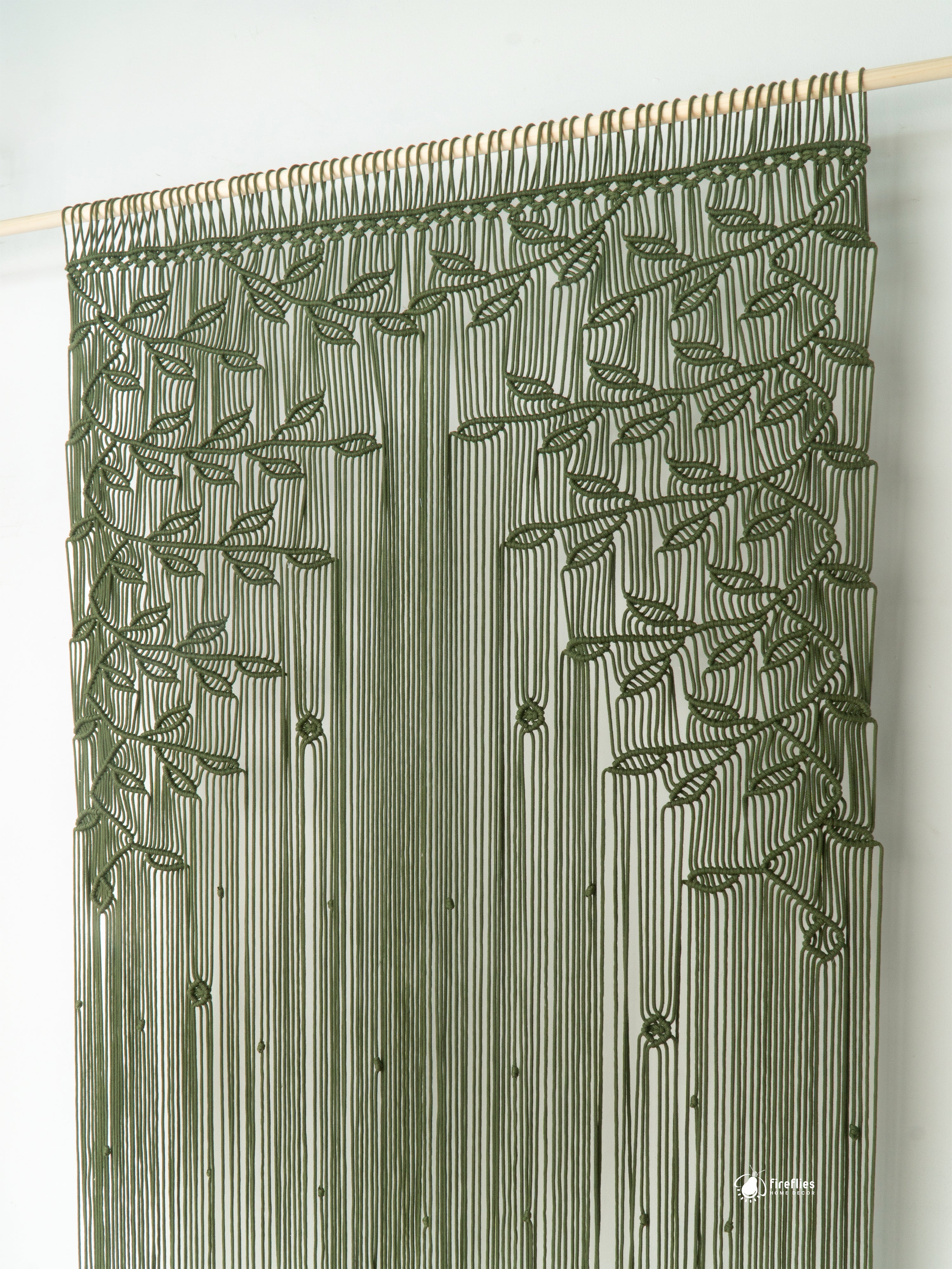 Decorative curtain with leaf pattern on a wooden rod against a white background