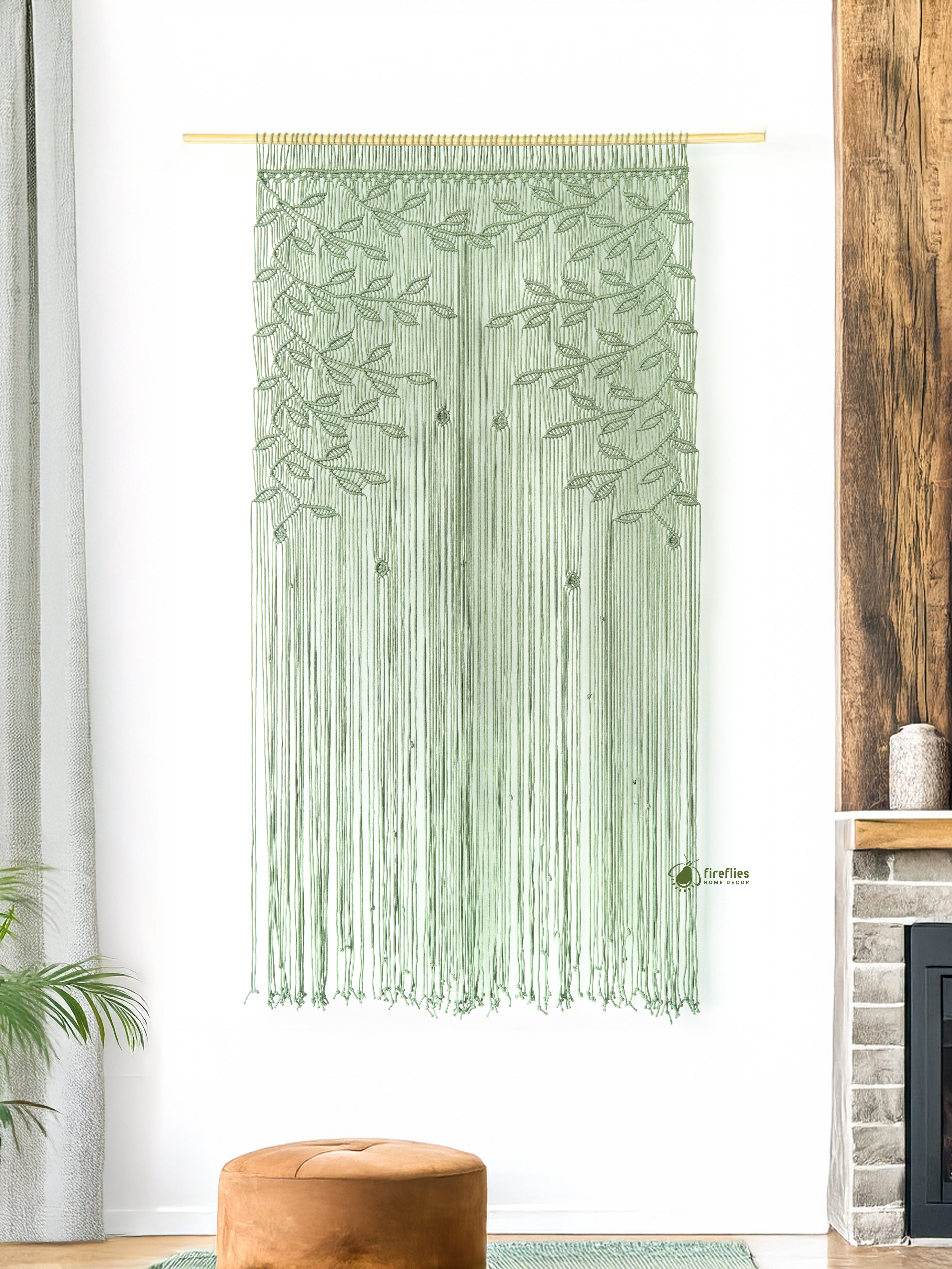 Green macramé curtain with leaf pattern hanging in a room with a wooden floor and white walls.