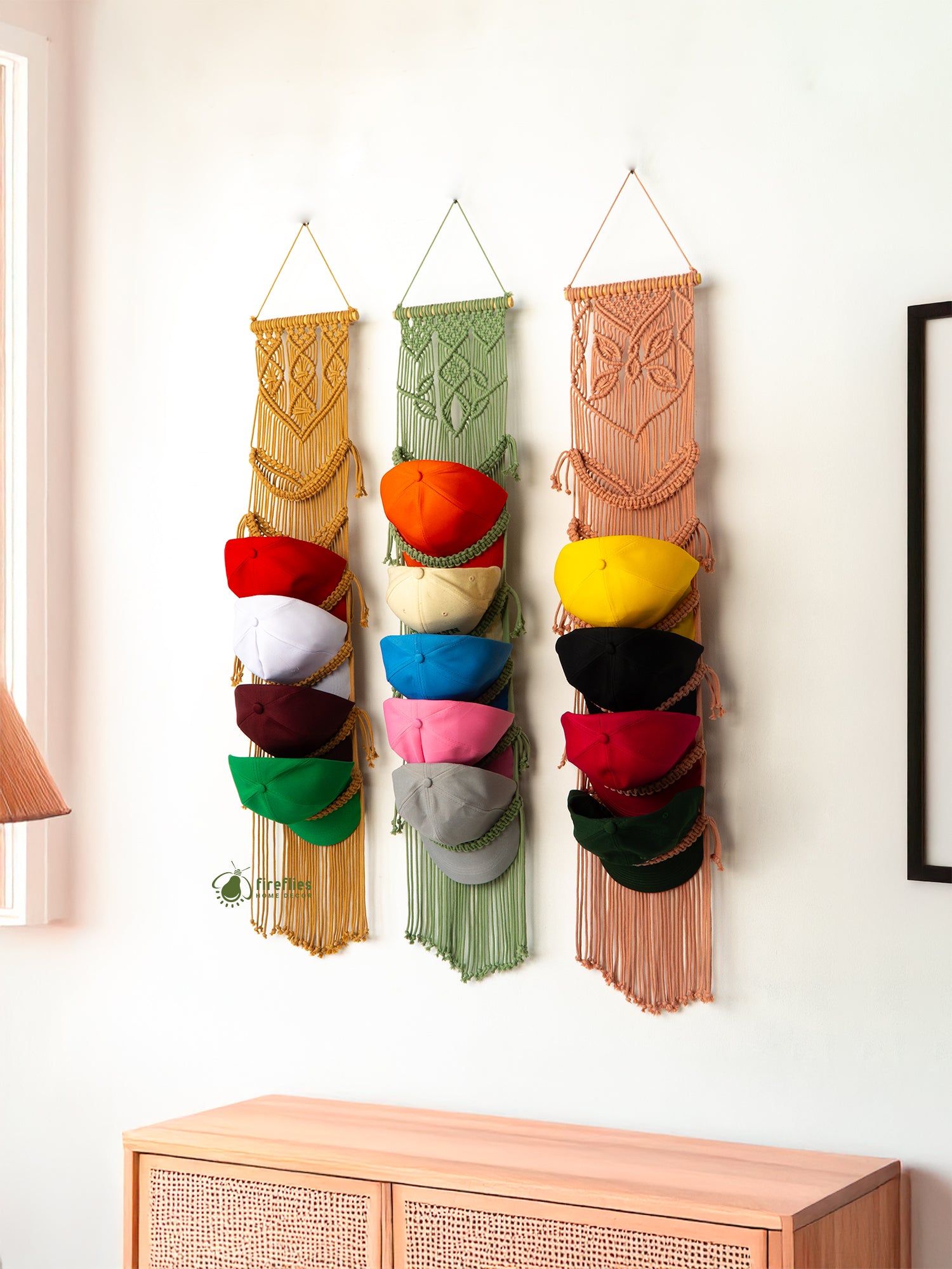 Colorful hat organizer hanging on a wall with a wooden cabinet below.