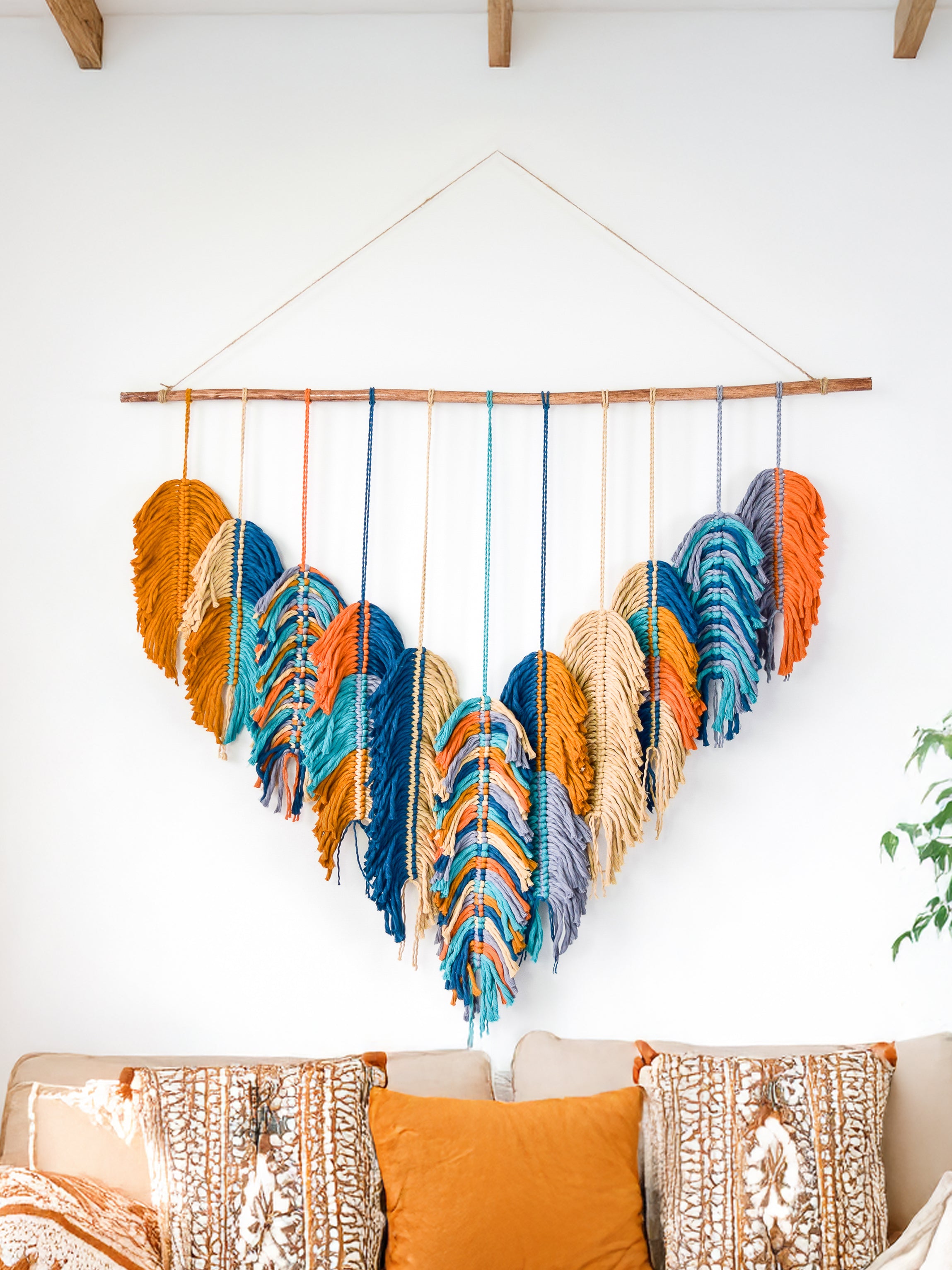 Colorful woven wall hanging above a sofa with patterned cushions.