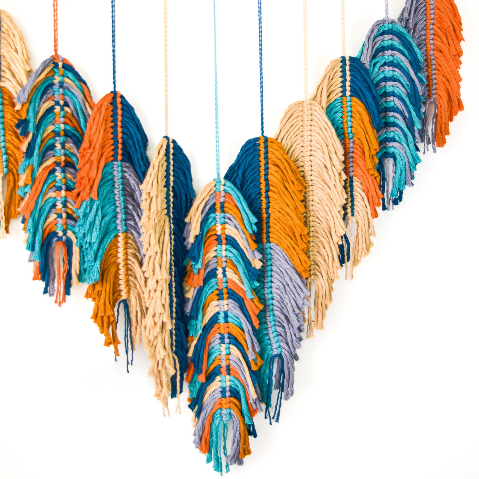 Colorful woven wall art with a geometric pattern on a white background