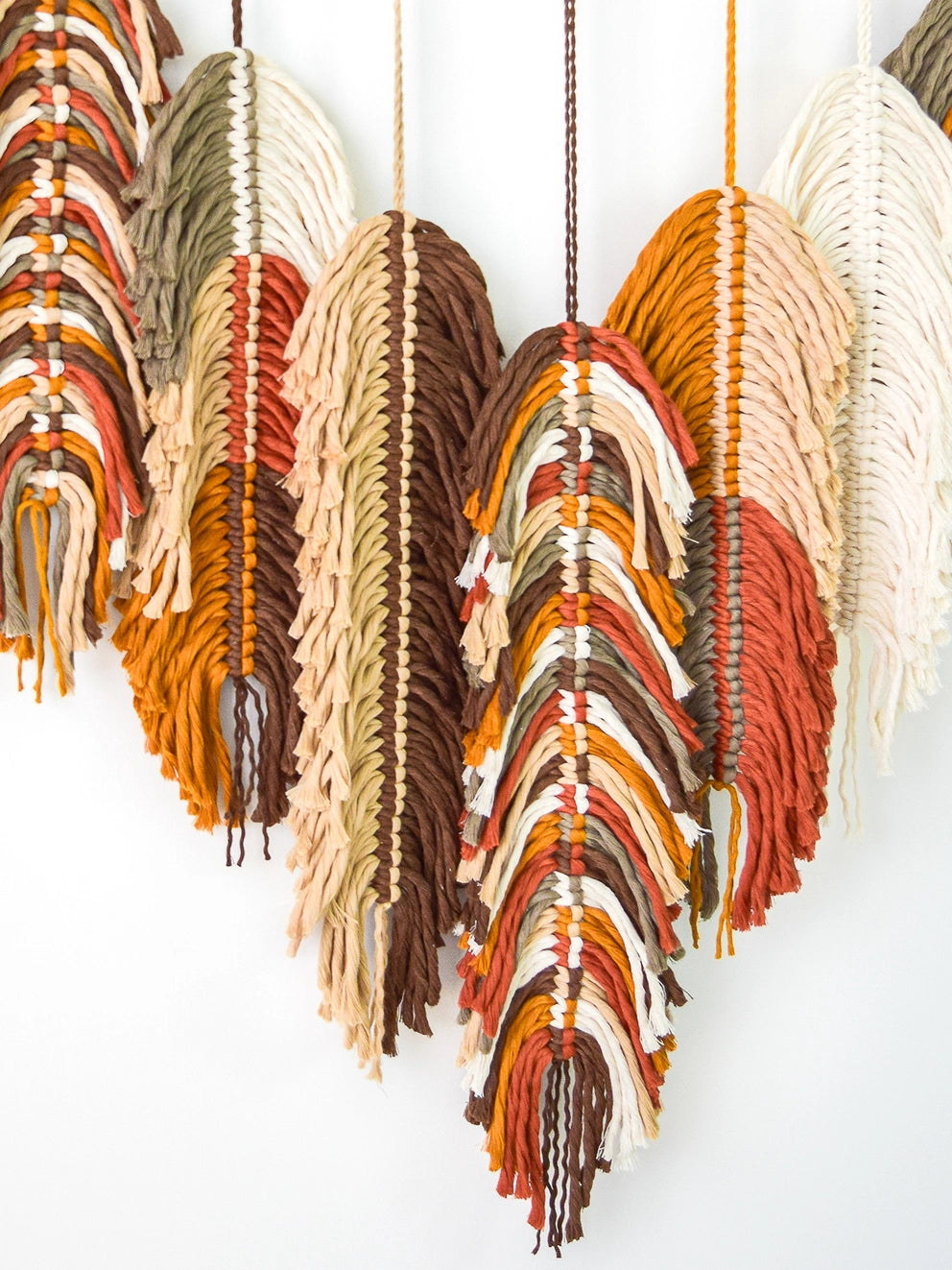 Decorative wall art with woven heart shapes in earthy tones on a white background