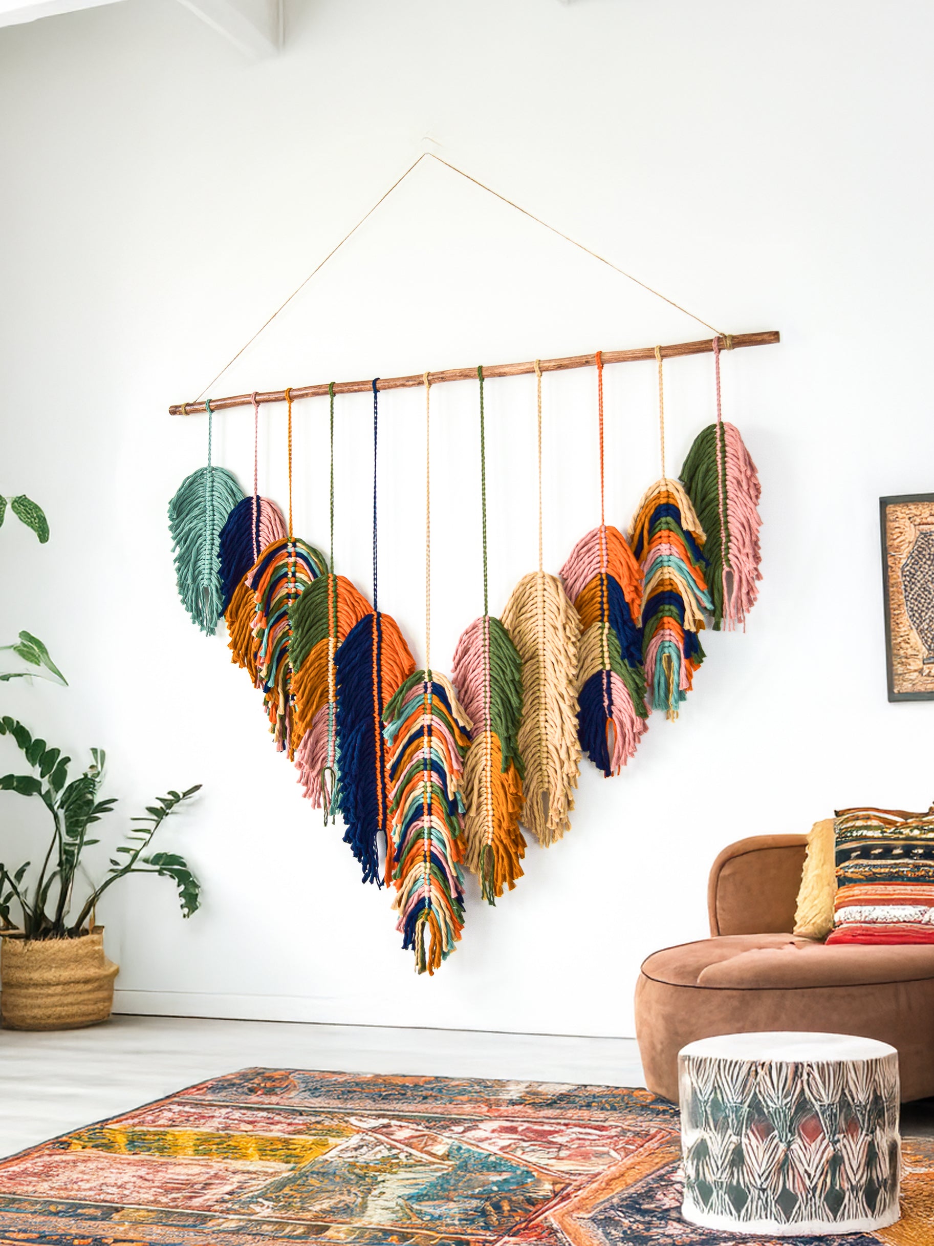Decorative wall hanging with heart-shaped feathers in a living room setting.
