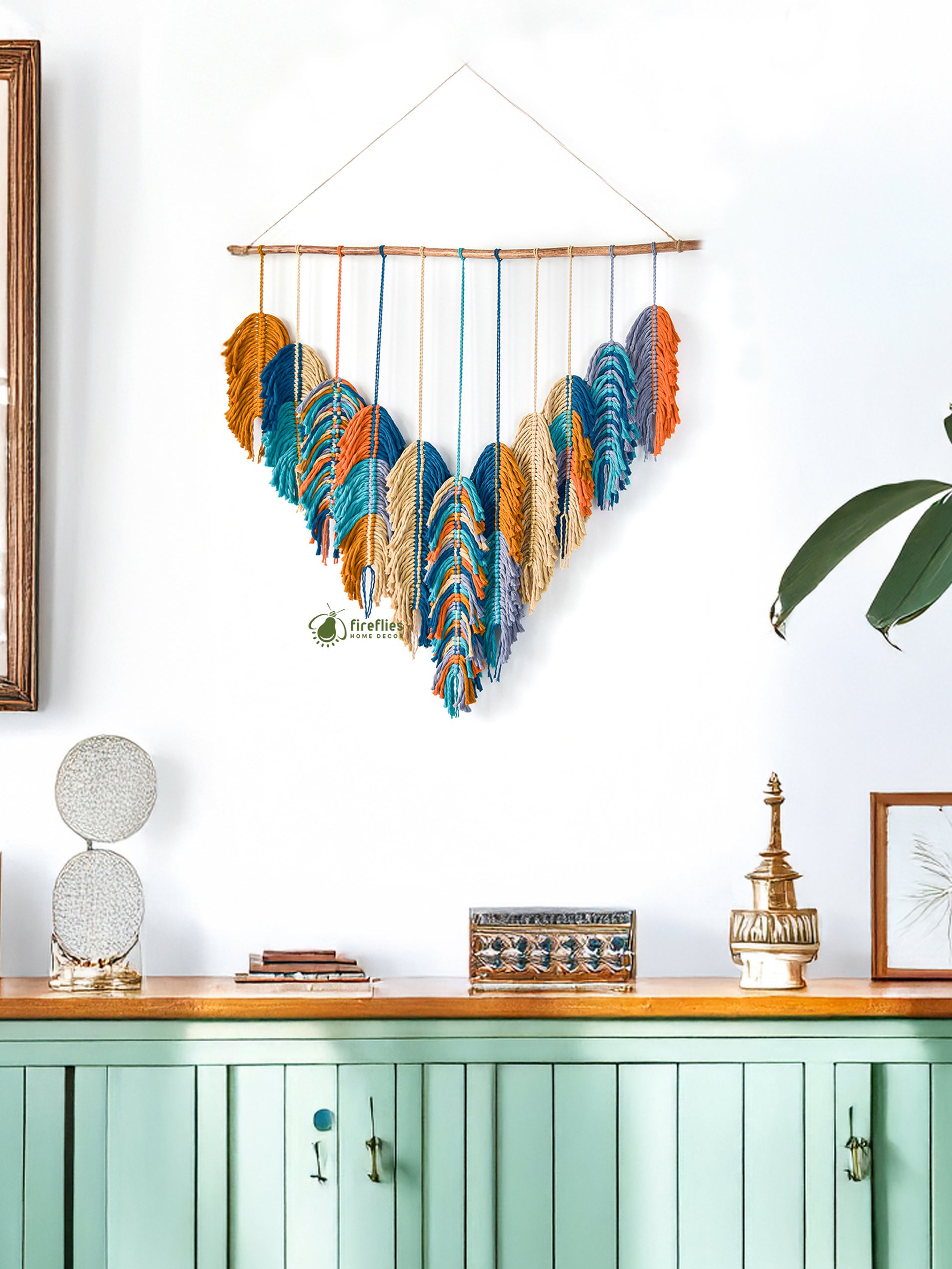 Decorative wall hanging with colorful feathers above a green cabinet.