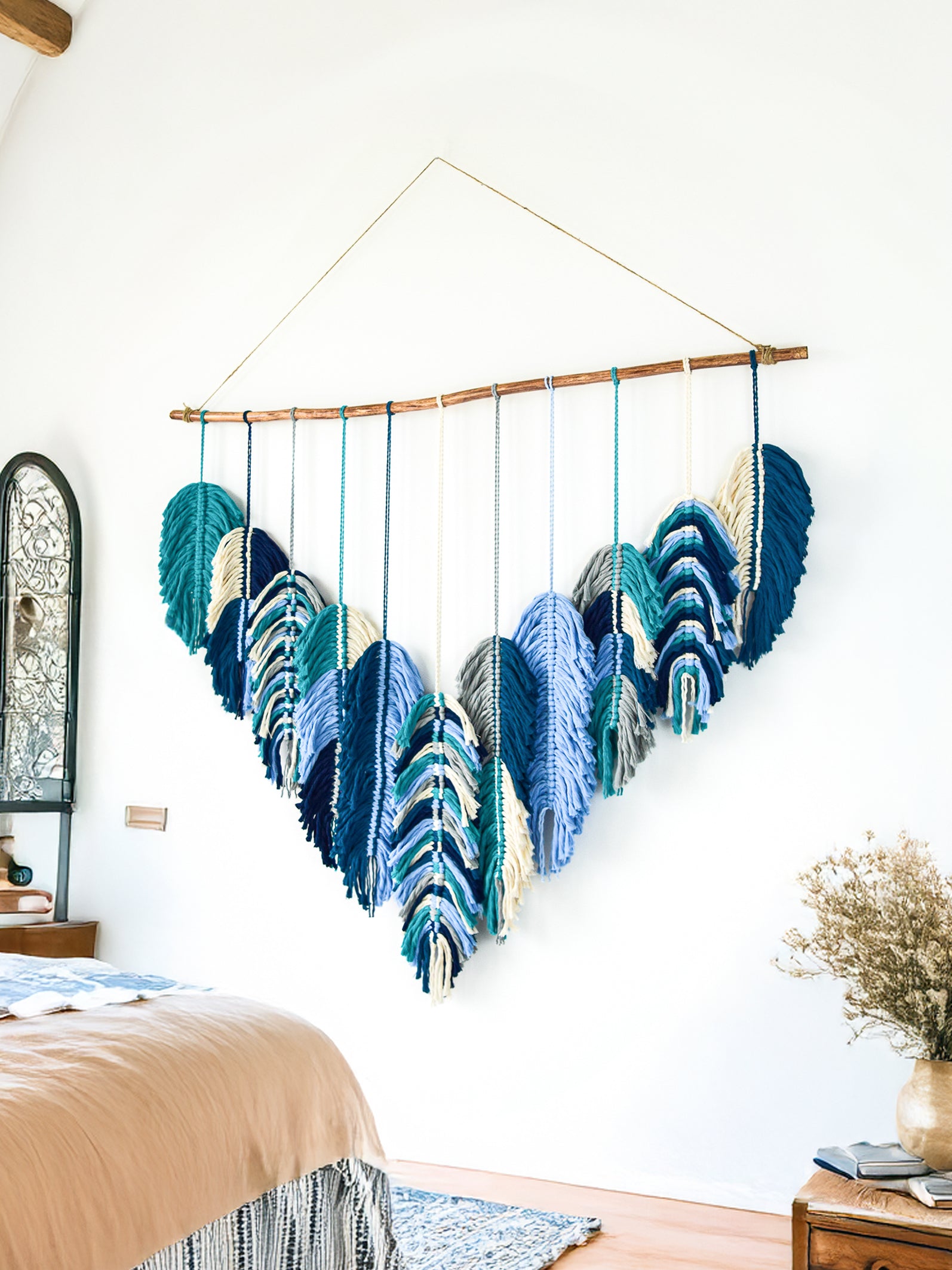 Colorful wall hanging in a living room with pink sofas and a white wall.