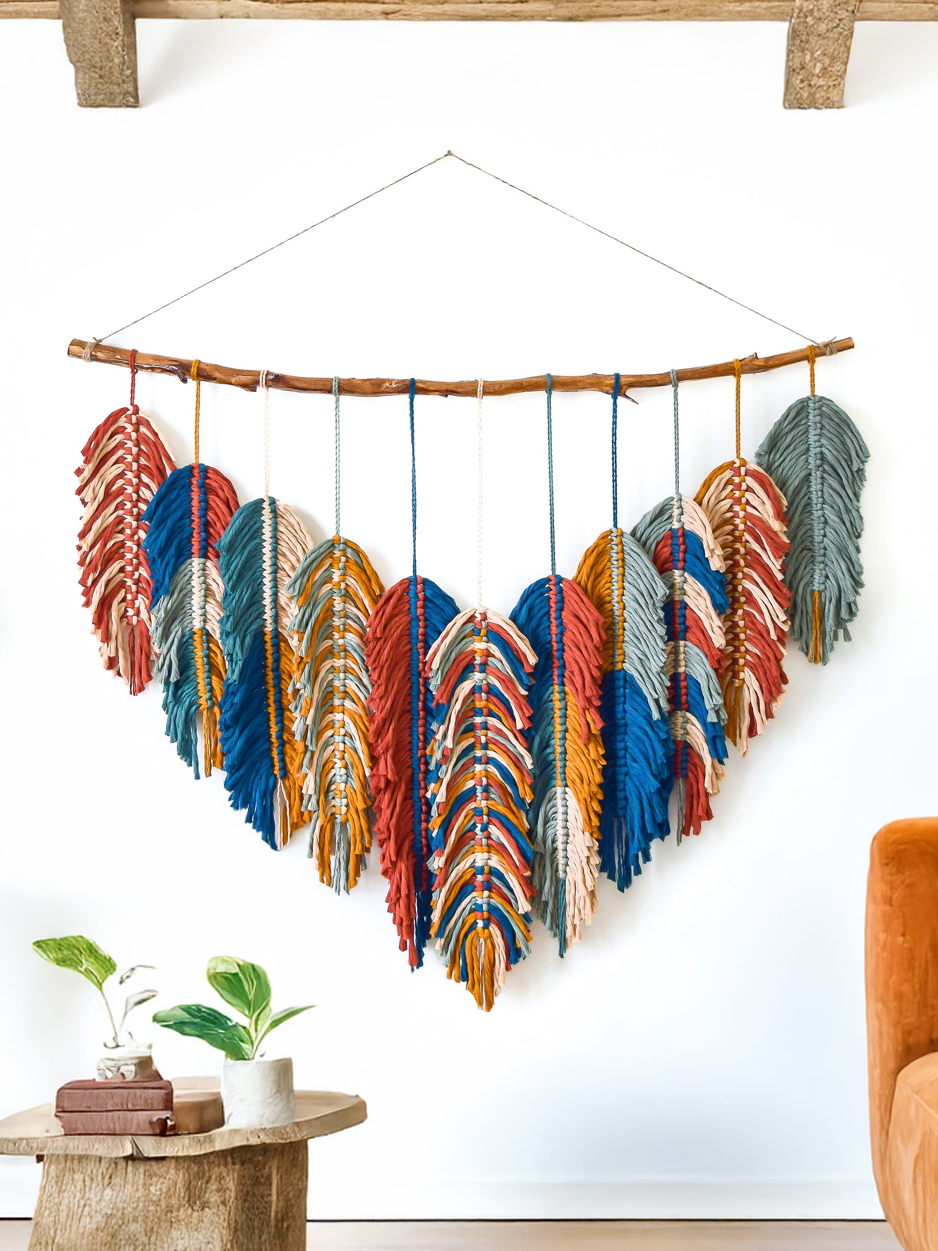 Decorative wall hanging with blue and green feathers in a room setting.