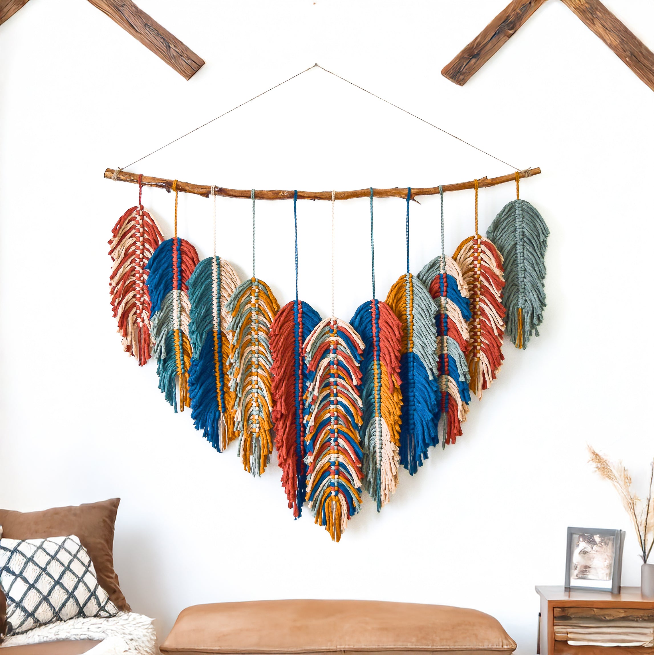 Colorful feather wall hanging on a white wall with wooden beams.
