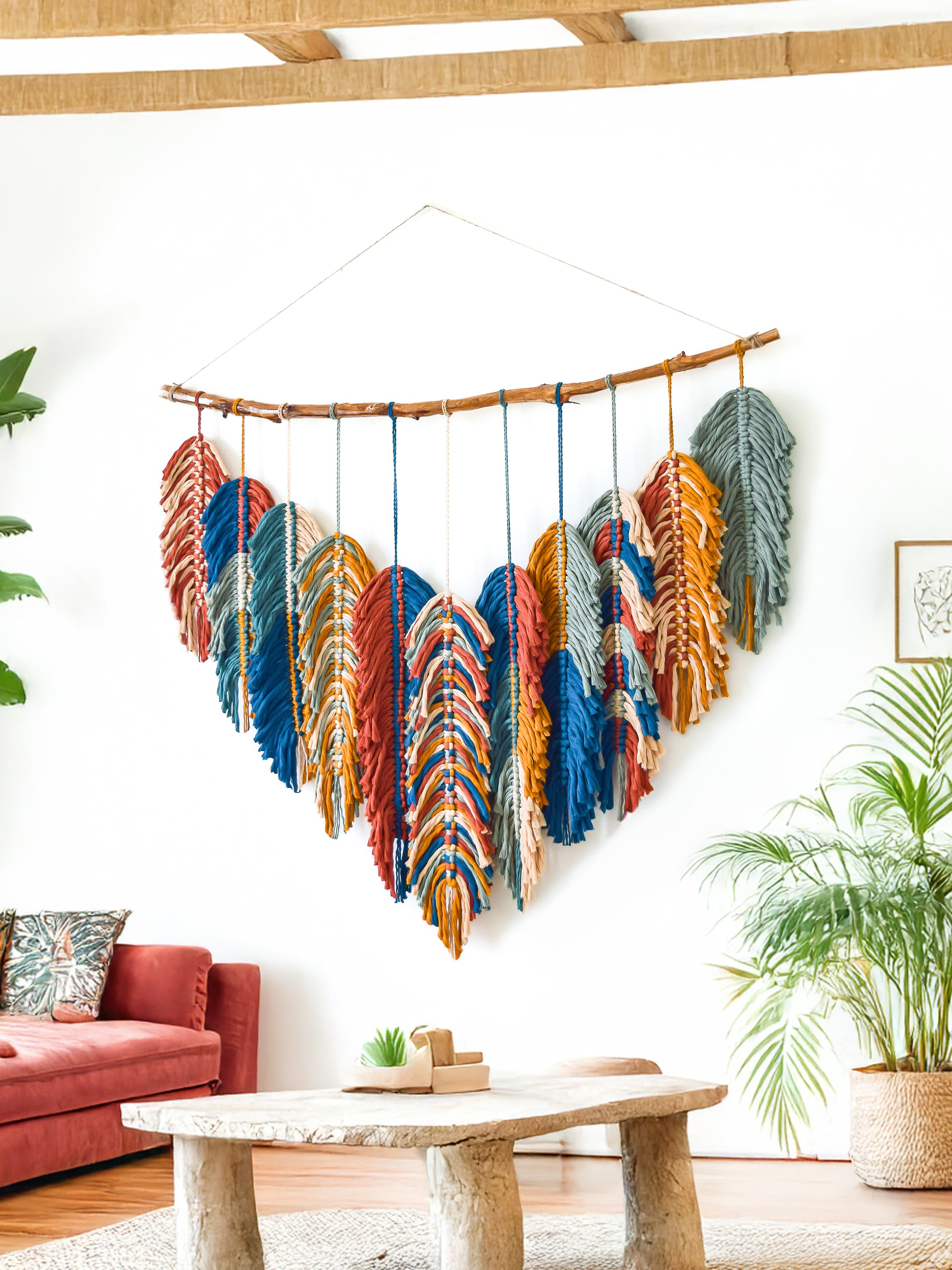 Decorative wall hanging with blue and green feathers in a living room setting.