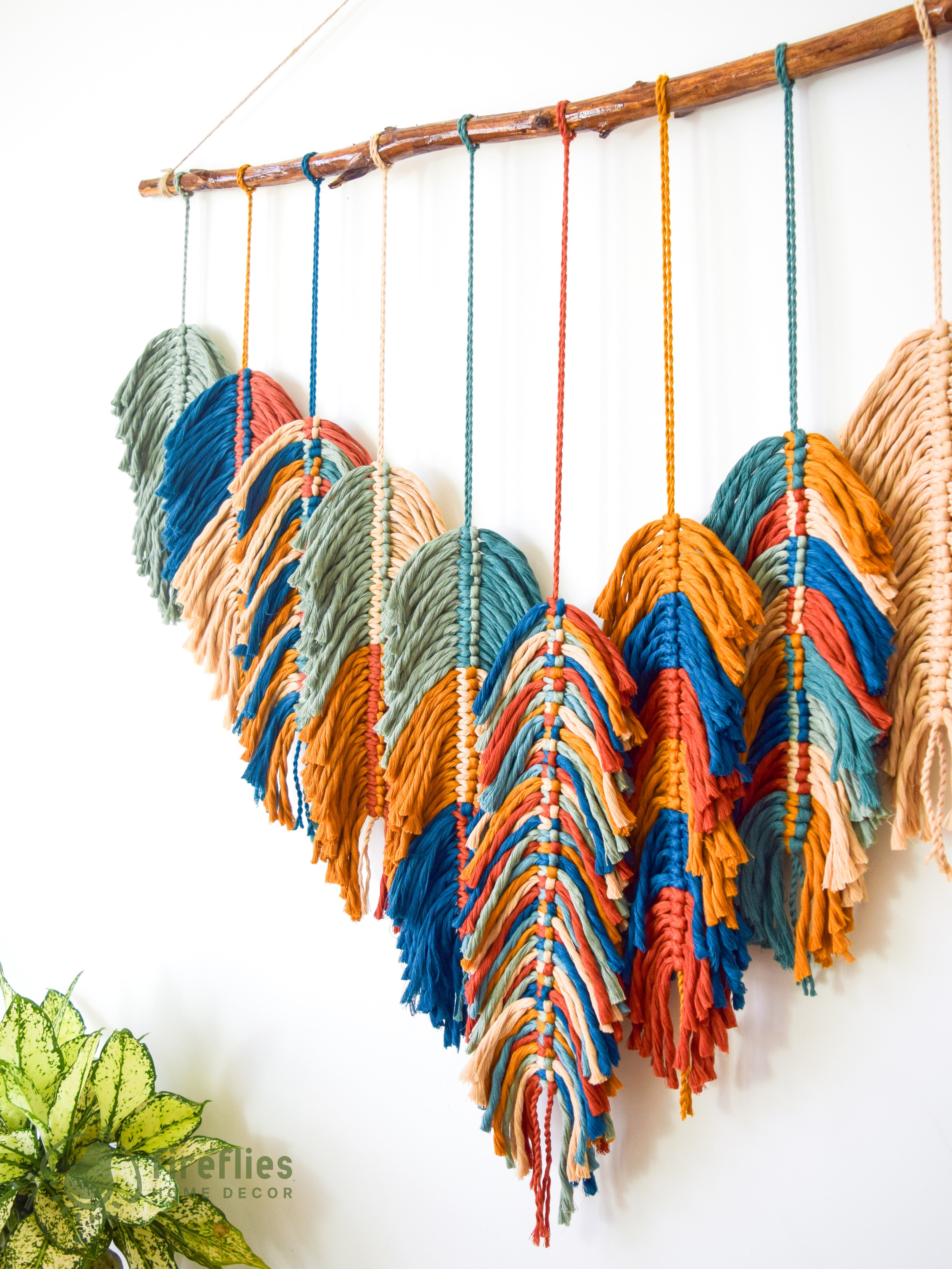 Colorful yarn hanging on a wooden rod against a white wall.
