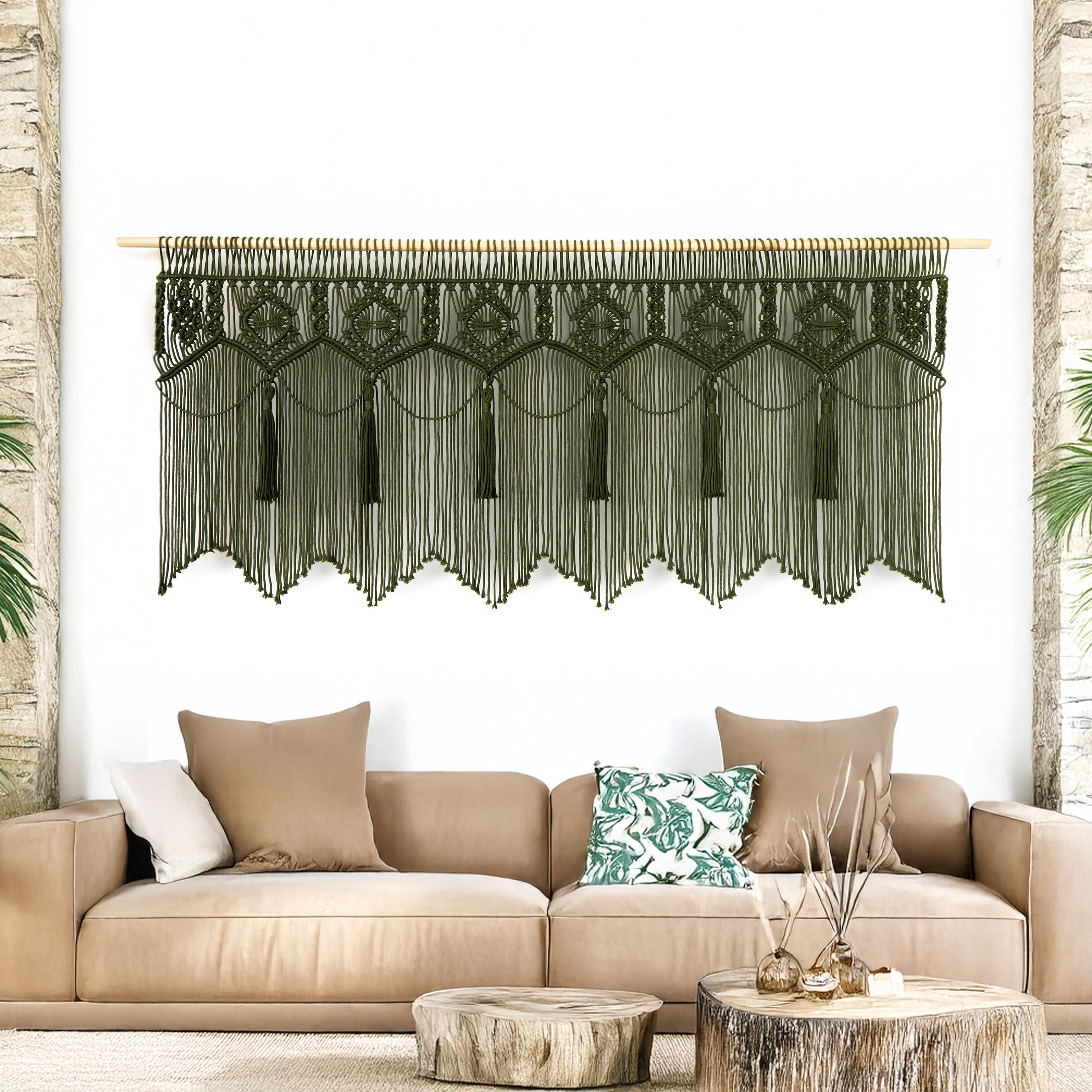 Decorative wall hanging with leaf patterns above a beige sofa with patterned cushions.