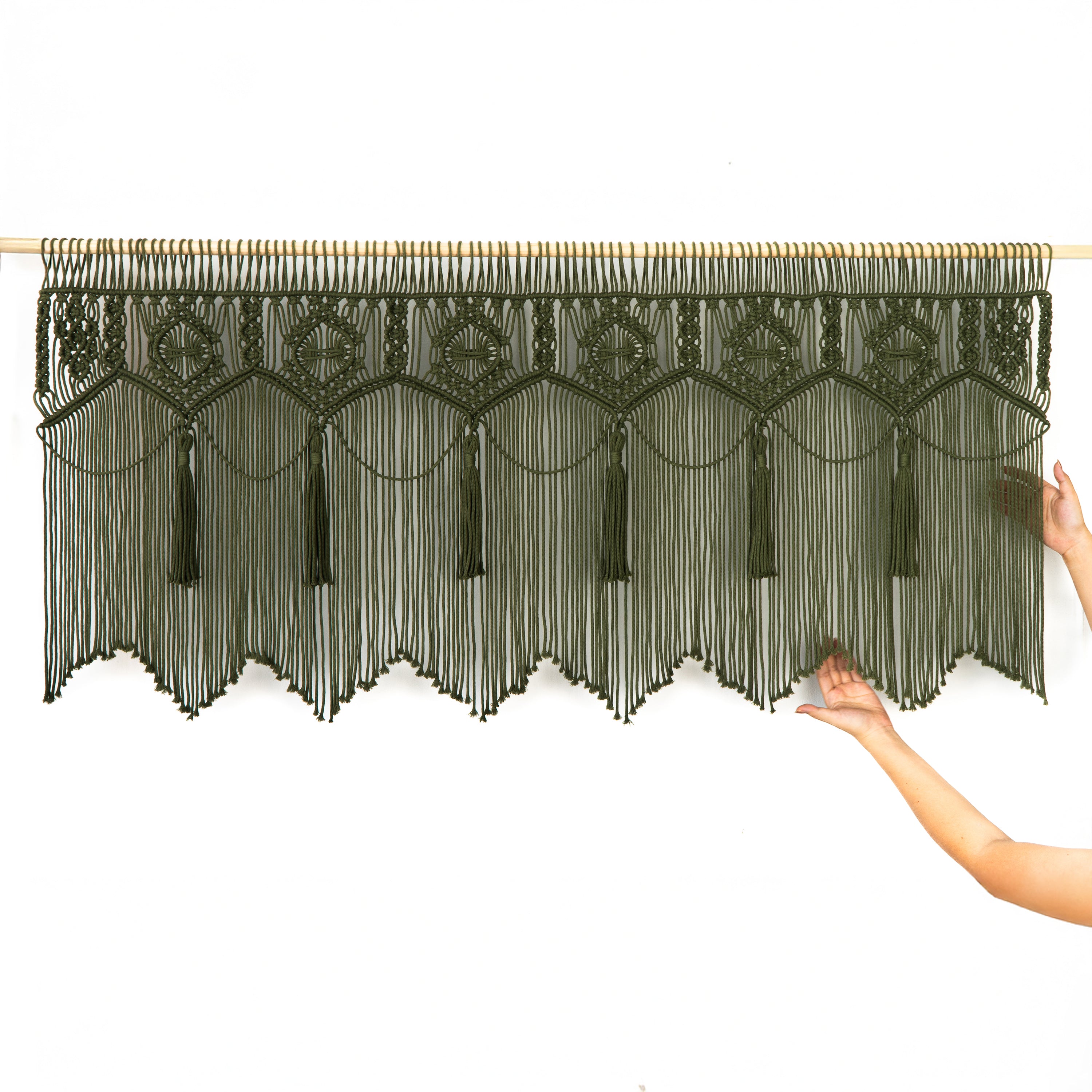 Decorative black string curtain with tassels held by a person on a white background