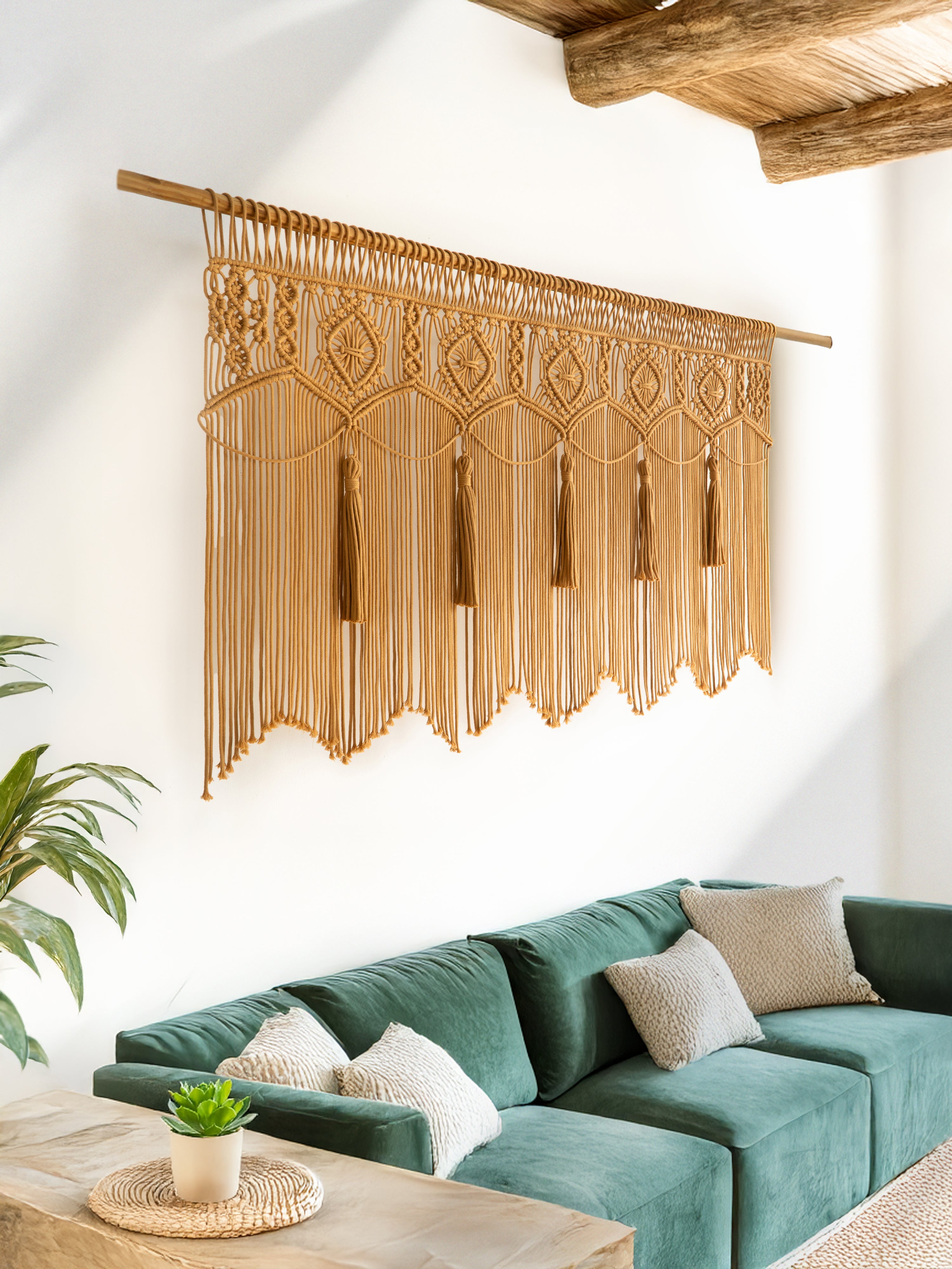 Decorative macrame wall hanging above a green sofa in a living room.