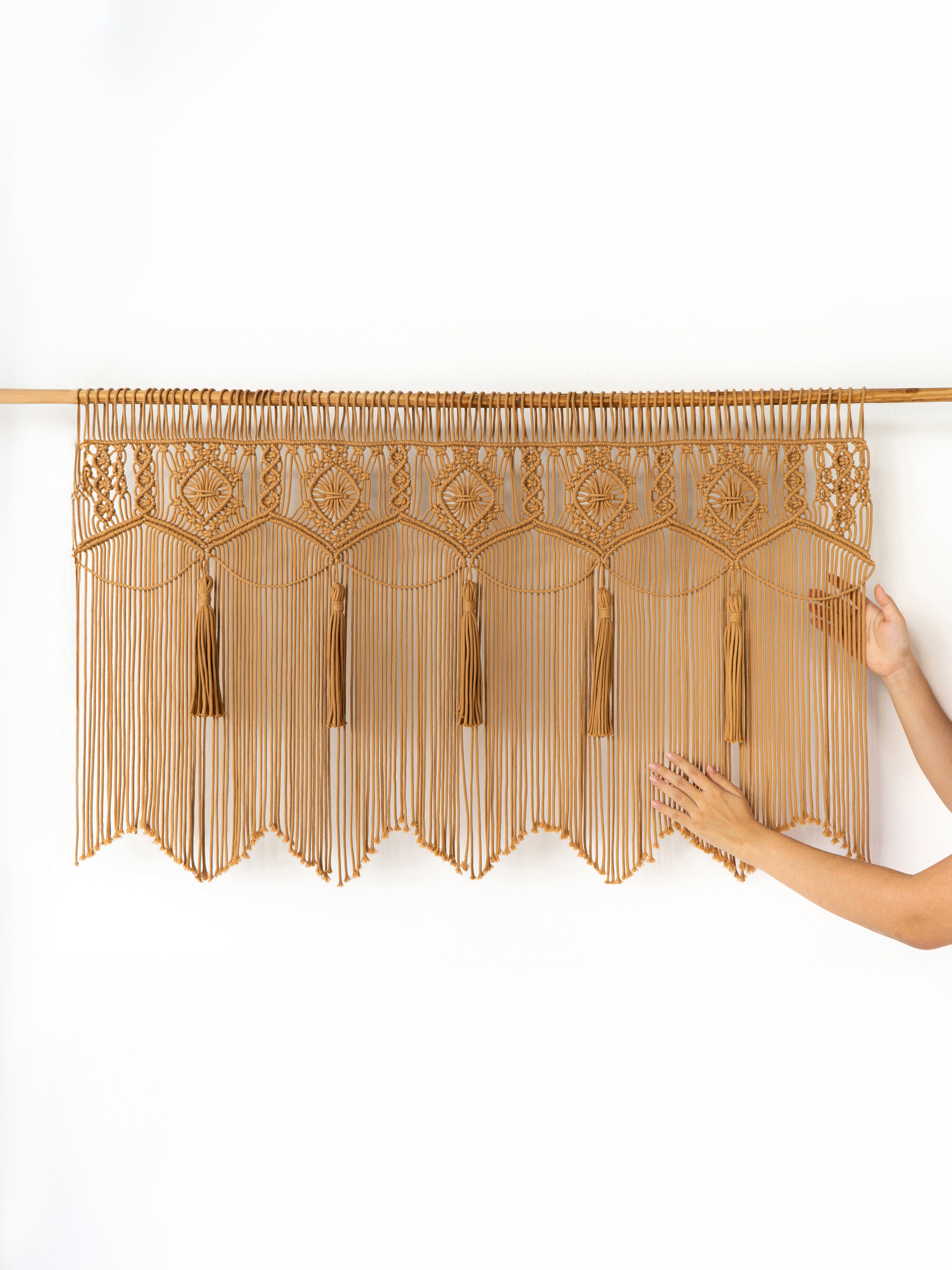 Decorative beige curtain with tassels on a white background