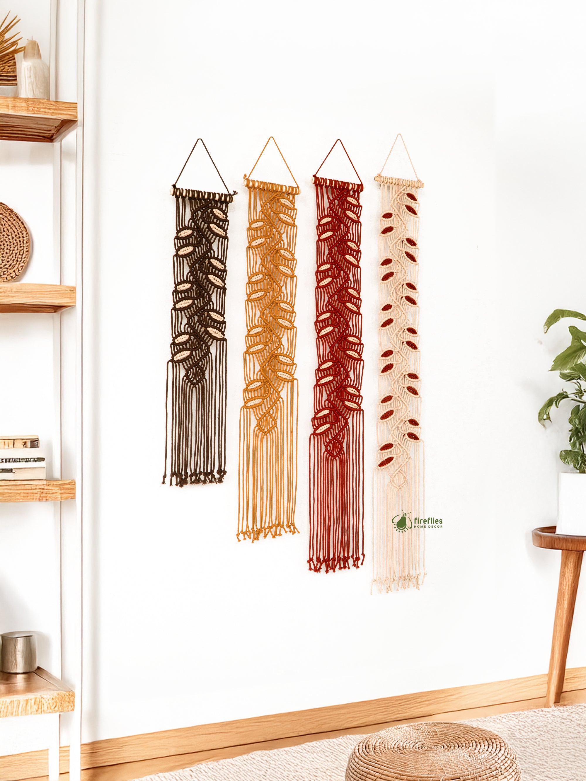 Four macrame wall hangings in different colors hanging on a white wall.