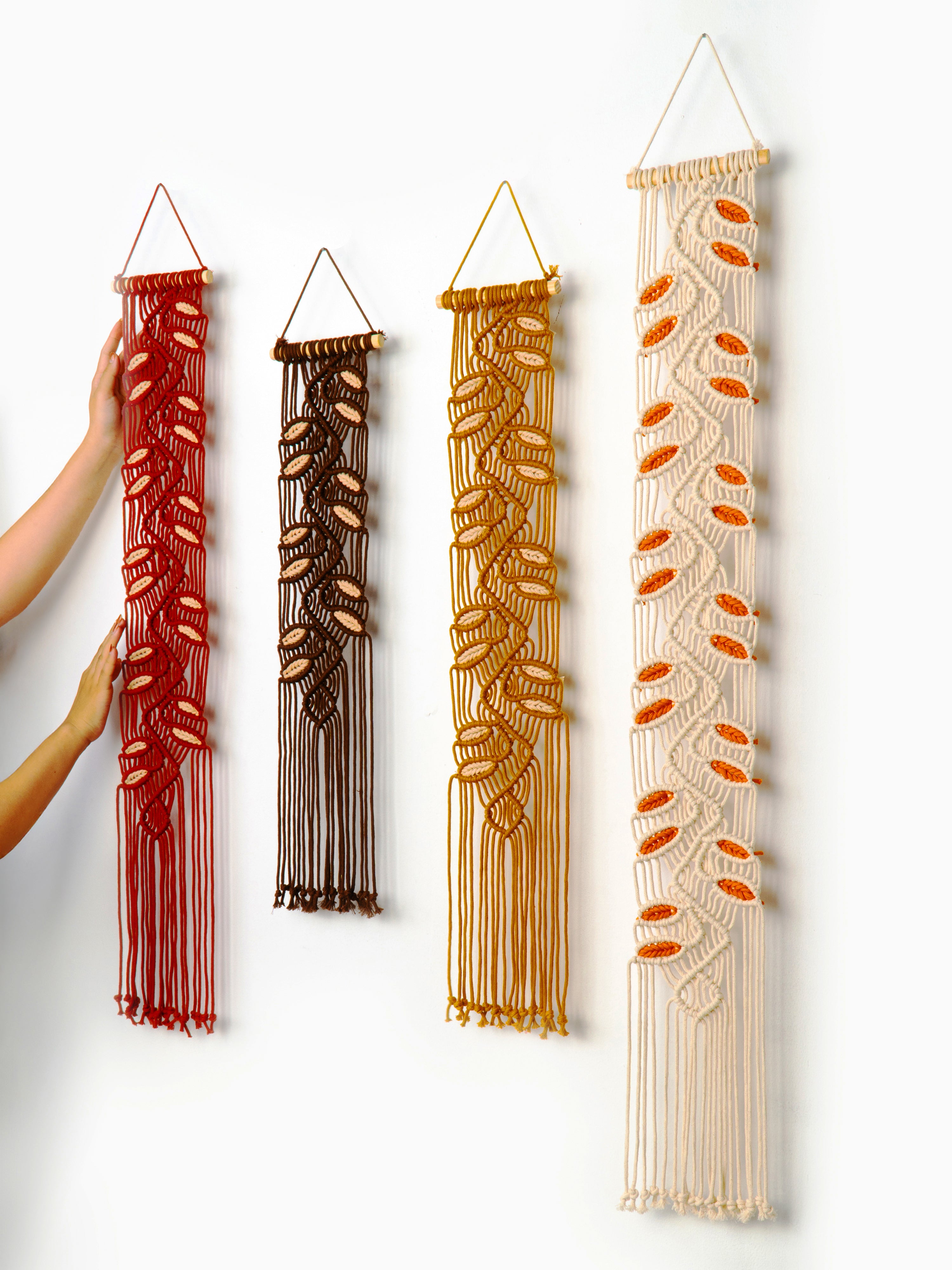 Set of four macrame wall hangings in different colors on a white background
