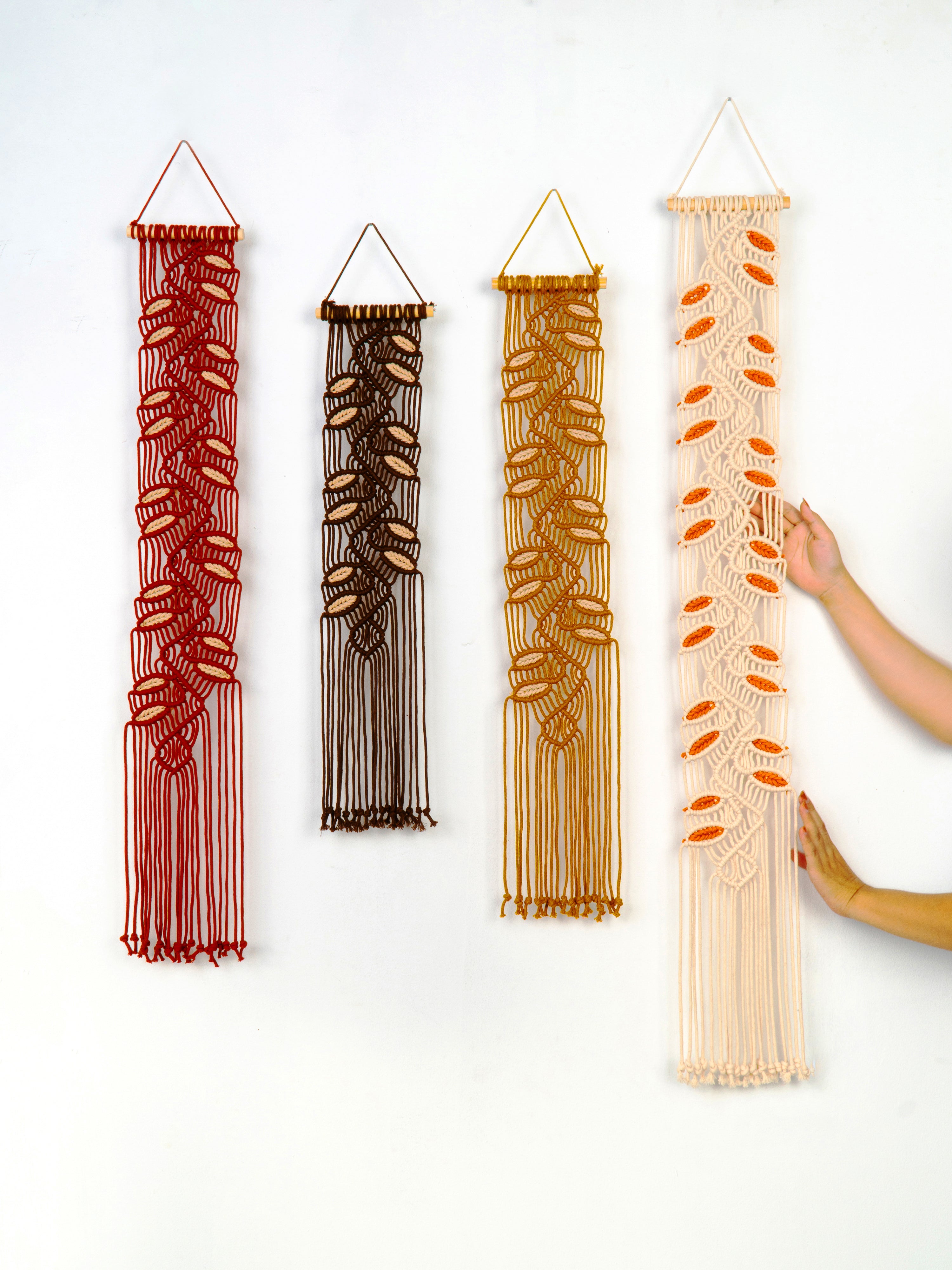 Four string art pieces in different colors hanging on a white wall.