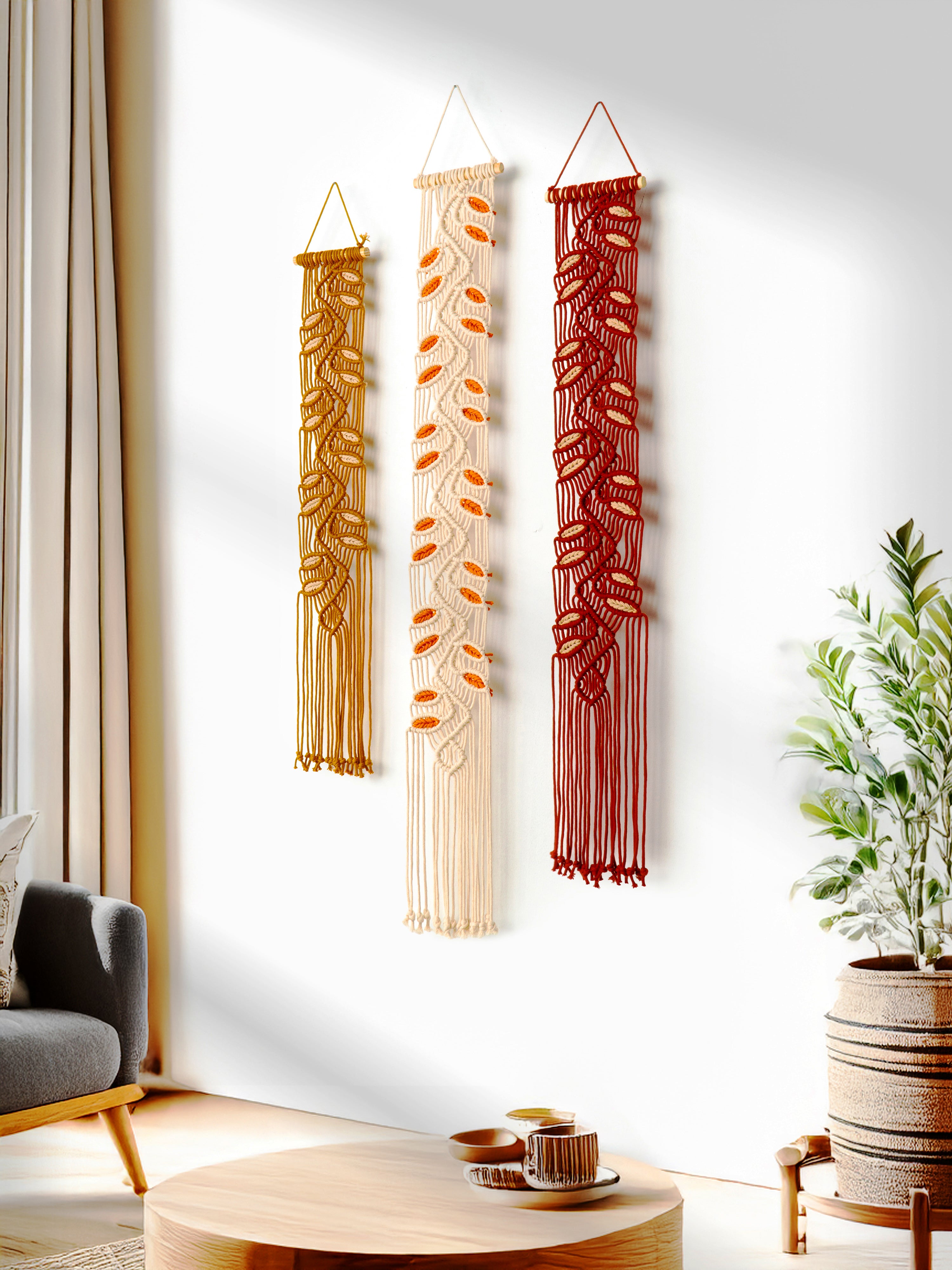 Three macrame wall hangings in different designs on a white wall with a living room setting.