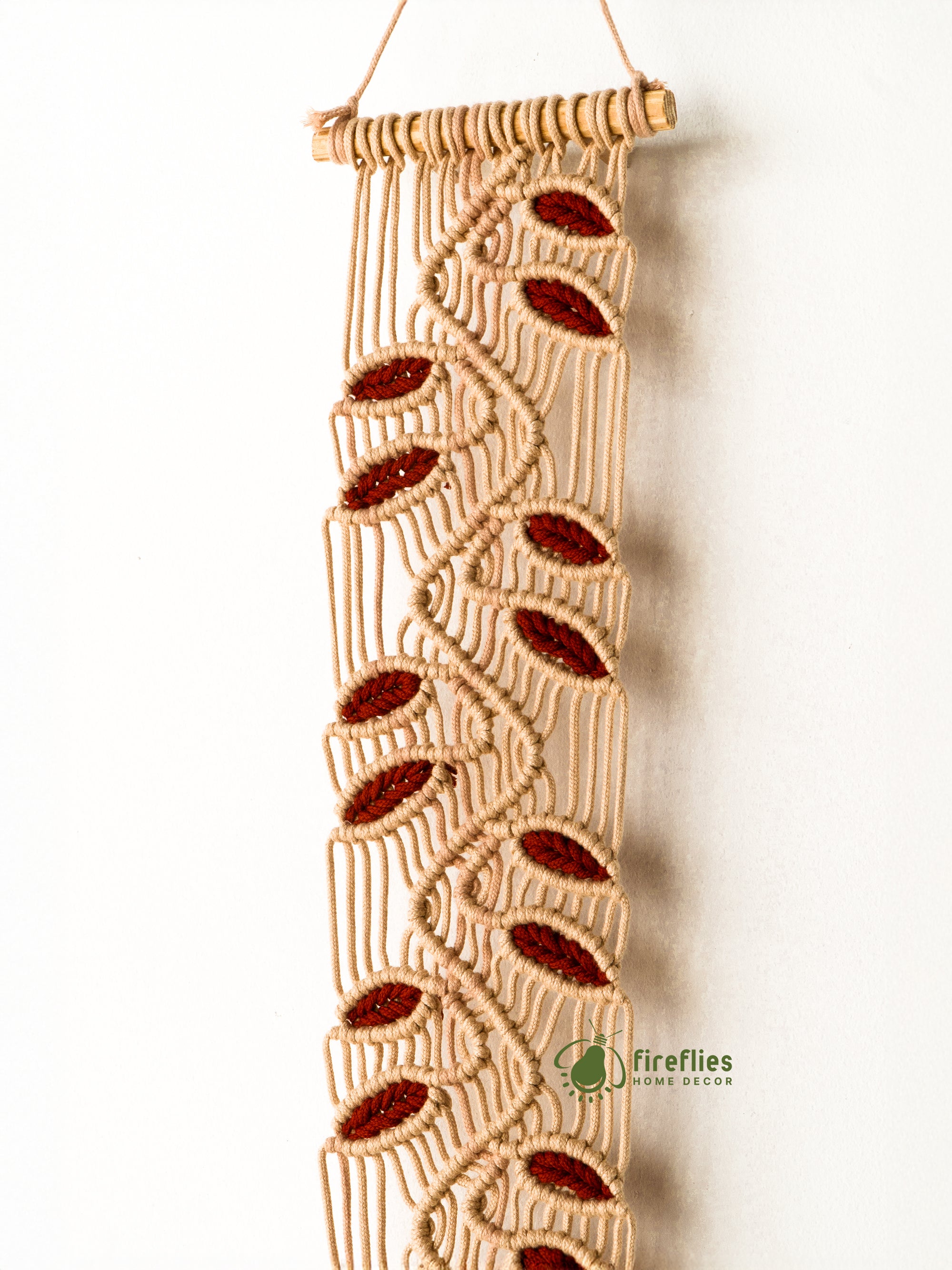 Macrame wall hanging with red accents on a white background, featuring the brand 'fireflies home decor'.