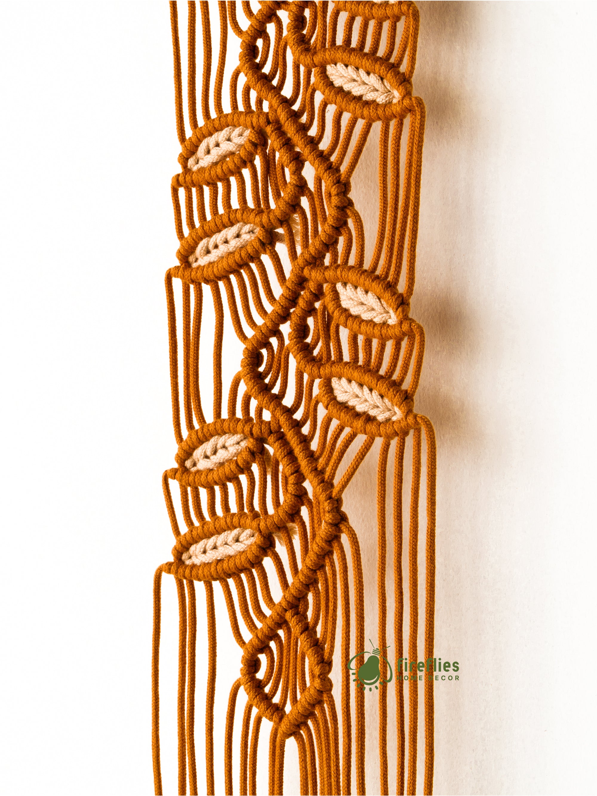 Macrame wall hanging with leaf patterns on a white background
